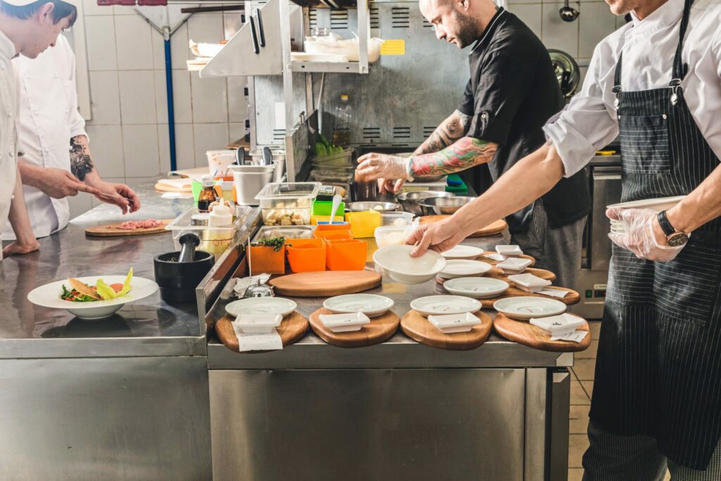 Chefkoch bereitet mit weiteren Mitarbeitern die Speisen zu