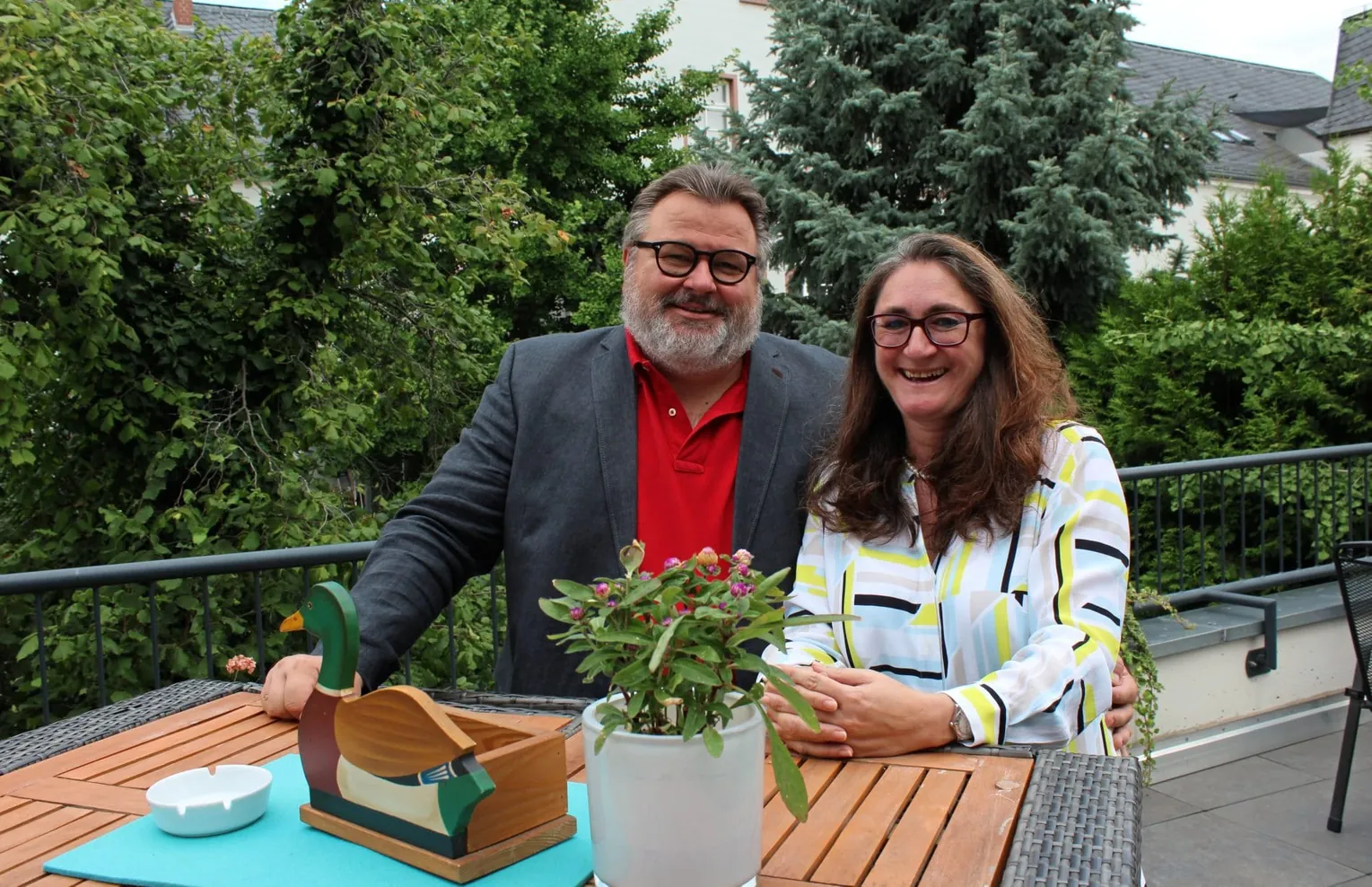 Peter und Ulla Häfner sitzen auf der Terrasse des Hotel Trapp und blicken lächelnd in die Kamera.