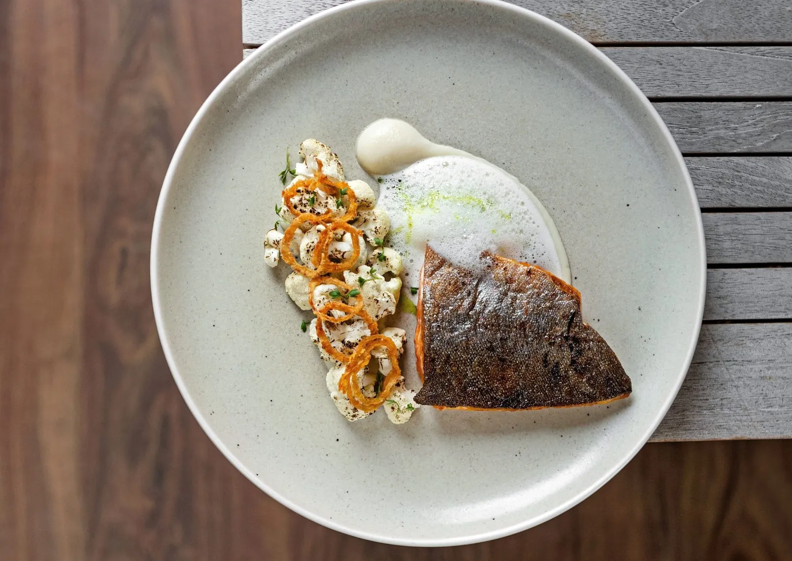 Bachsaibling mit Blumenkohl und Zwiebel-Kamillen-Schaum auf einem Teller