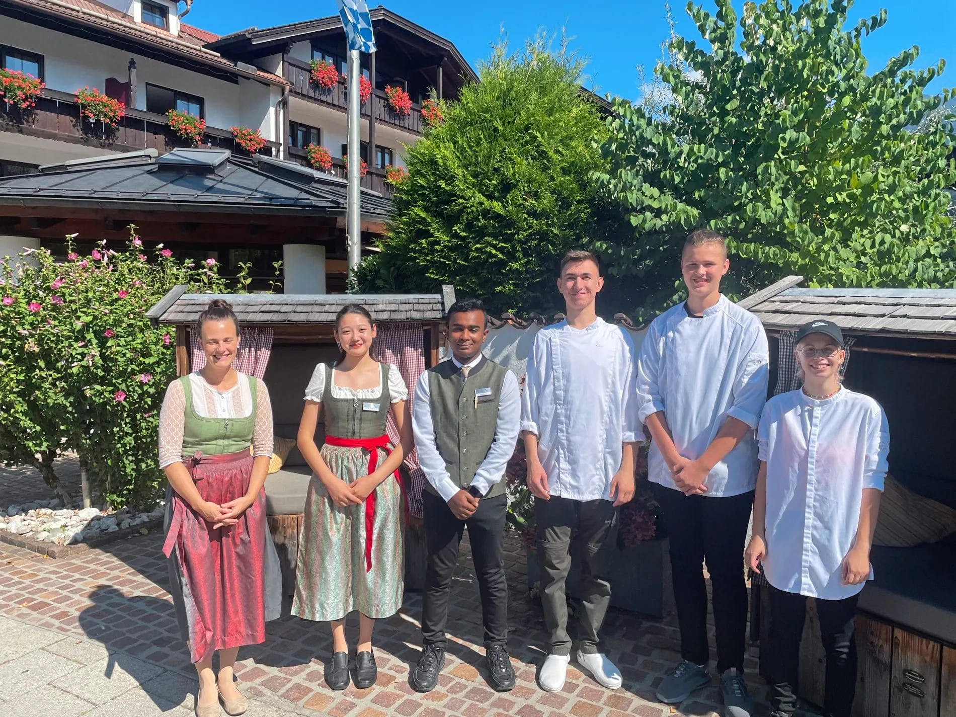 Sechs Azubis lächeln vor dem Hotel Zugspitze in die Kamera