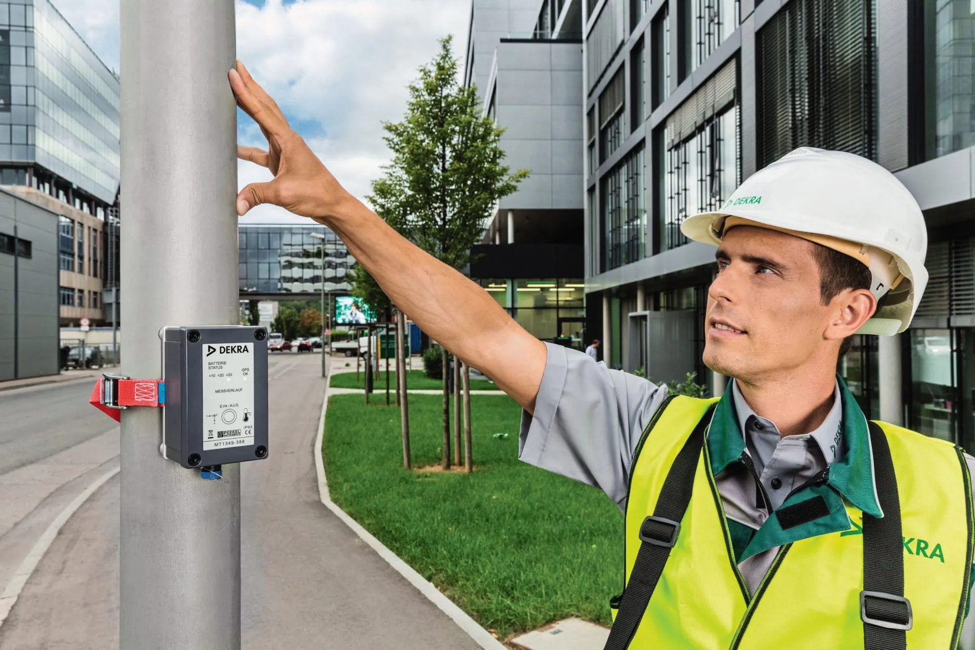 Mann prüft die Standfestigkeit eines Laternenmast.