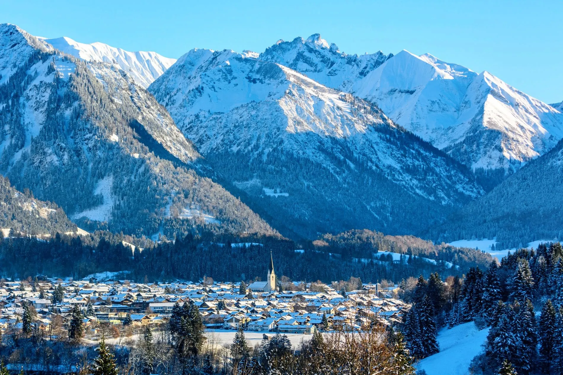 Wintersaison 2024/25, Panoramabild einen Dorfes im Allgäu vor den Begern