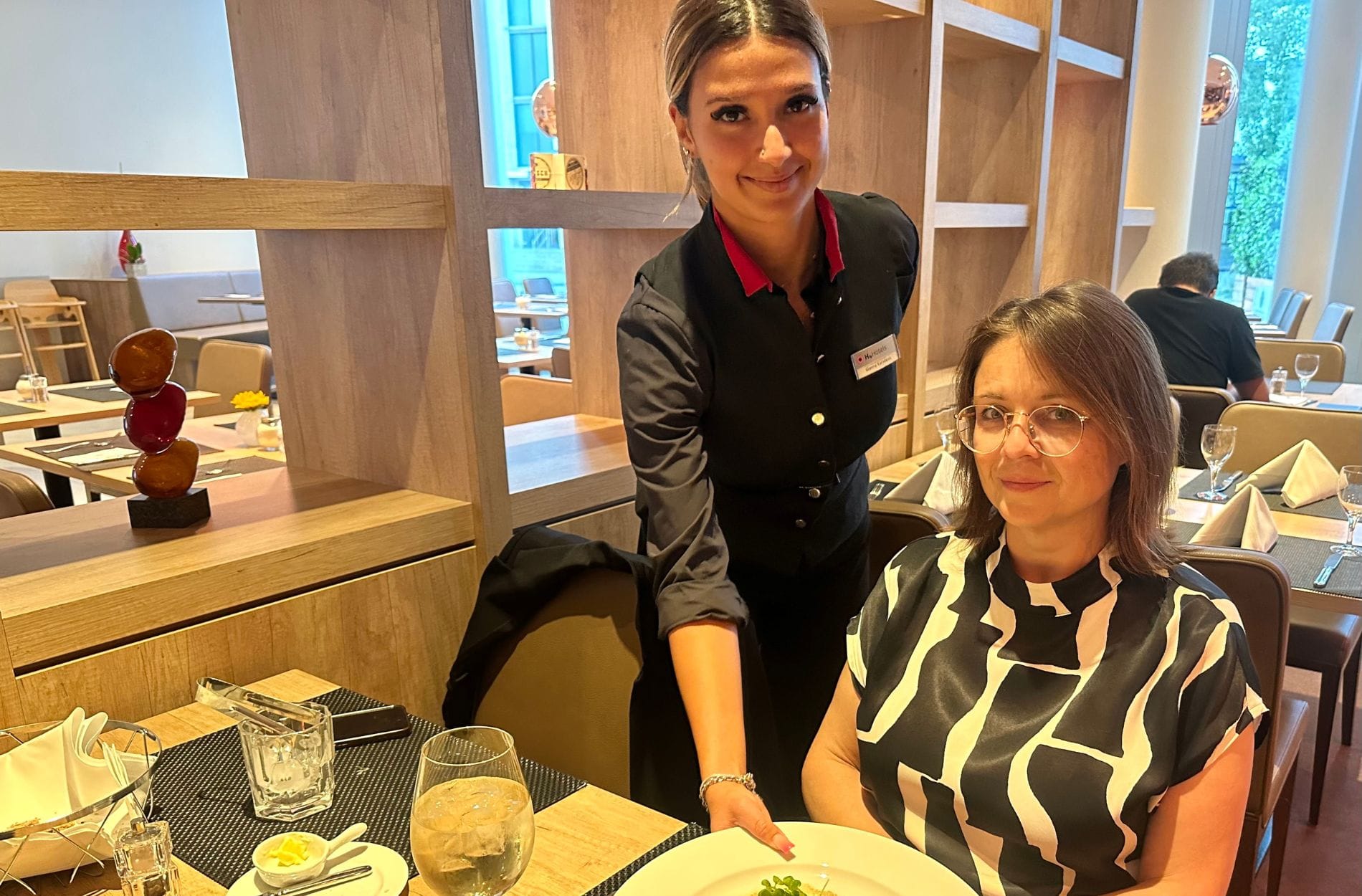 Gianna Karadeniz, Auszubildene zur Hotelfachfrau, serviert Jessica Borowiak, Area Managerin der Münchner H-Hotels, Zander an Graupenrisotto als Hauptspeise
