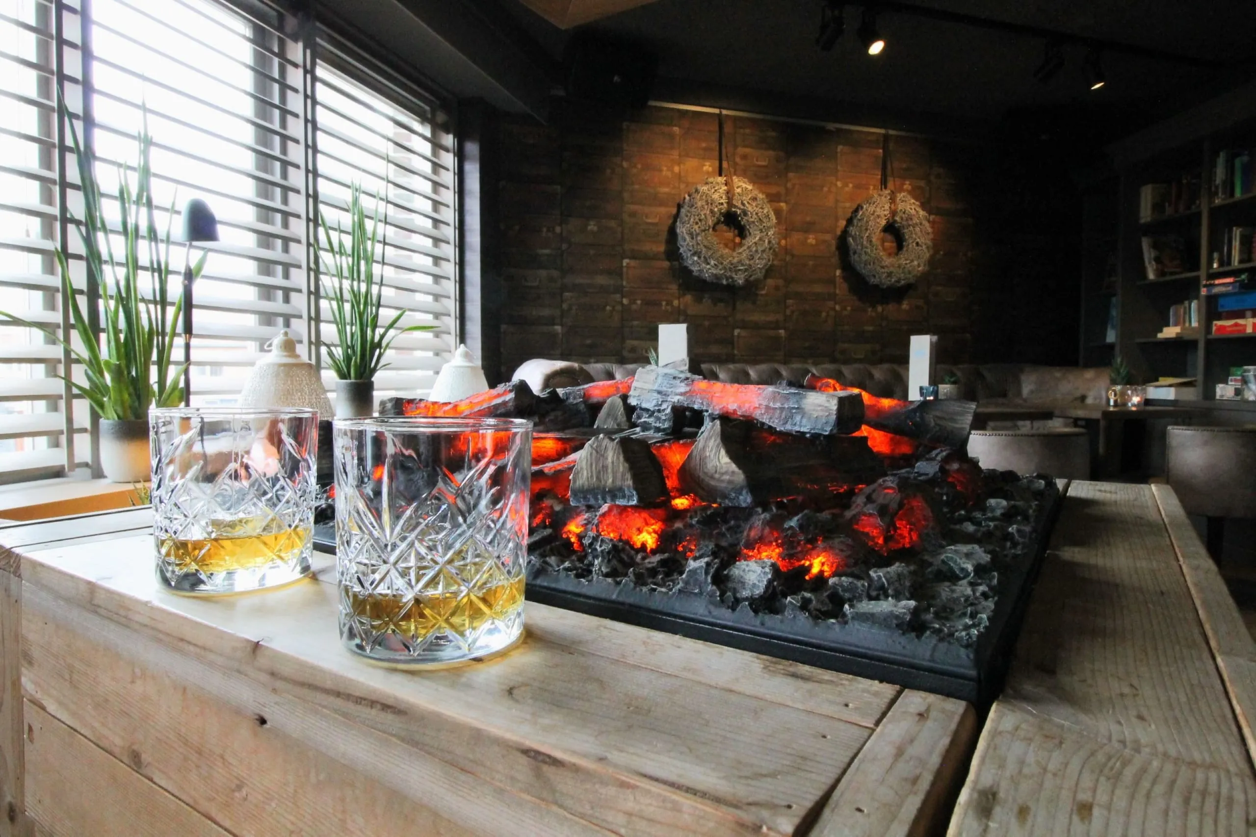Barbereich im Best Western Beach Hotel Bergen aan Zee mit Kaminfeuer und Whiskeysortiment.