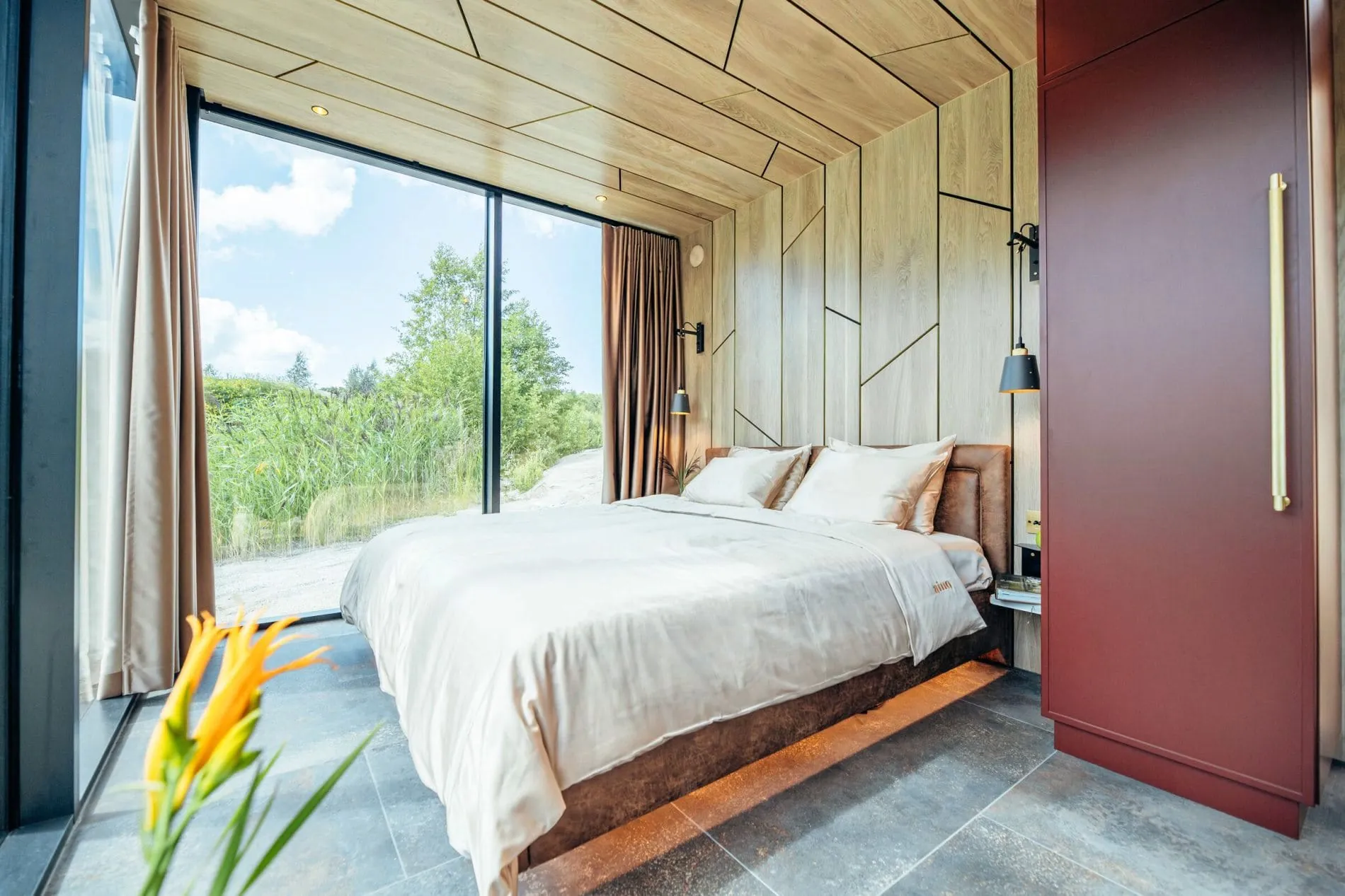 Steinböden und geometrische Holzverkleidungen sollen für eine ruhige Atmosphäre sorgen, die durch dezente Farbakzente in Rot belebt wird.