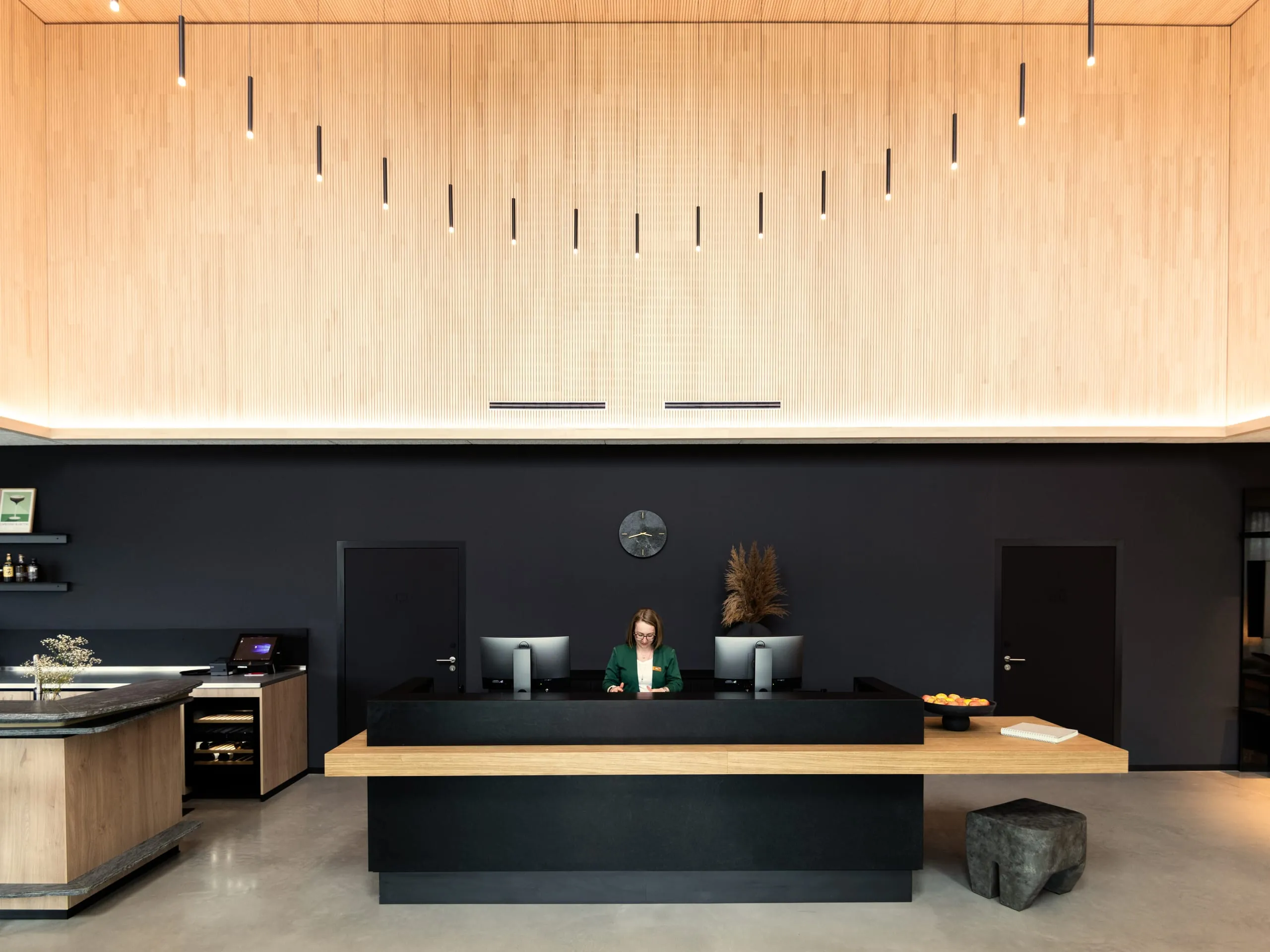 Über dem Empfangstresen thront eine kreisförmige Lichtskulptur aus schwarzen Pendelleuchten.