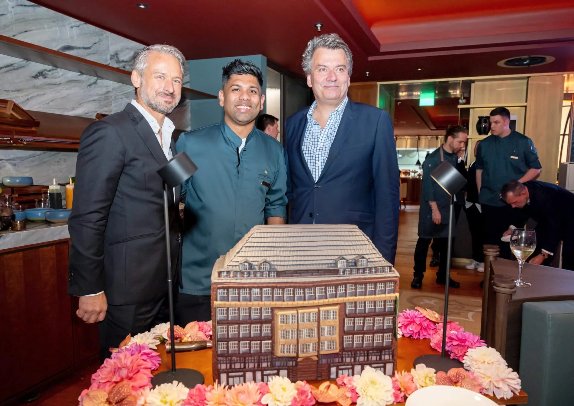Opening-Gala: Michael Wagner, COO MHP Hotel AG, Patissier Roshlee Cardoso und Dietmar Hamm, Geschäftsführer Kontorhausverwaltung Bach, mit einer außergewöhnlichen Patisserie-Kreation: einer Torte in Form des Levantehauses.