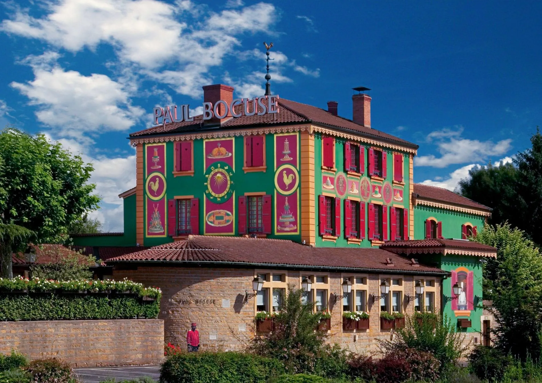 Das Auberge du Pont de Collonges zeichnet sich durch seine grüne Fassade mit roten Fensterläden aus.
