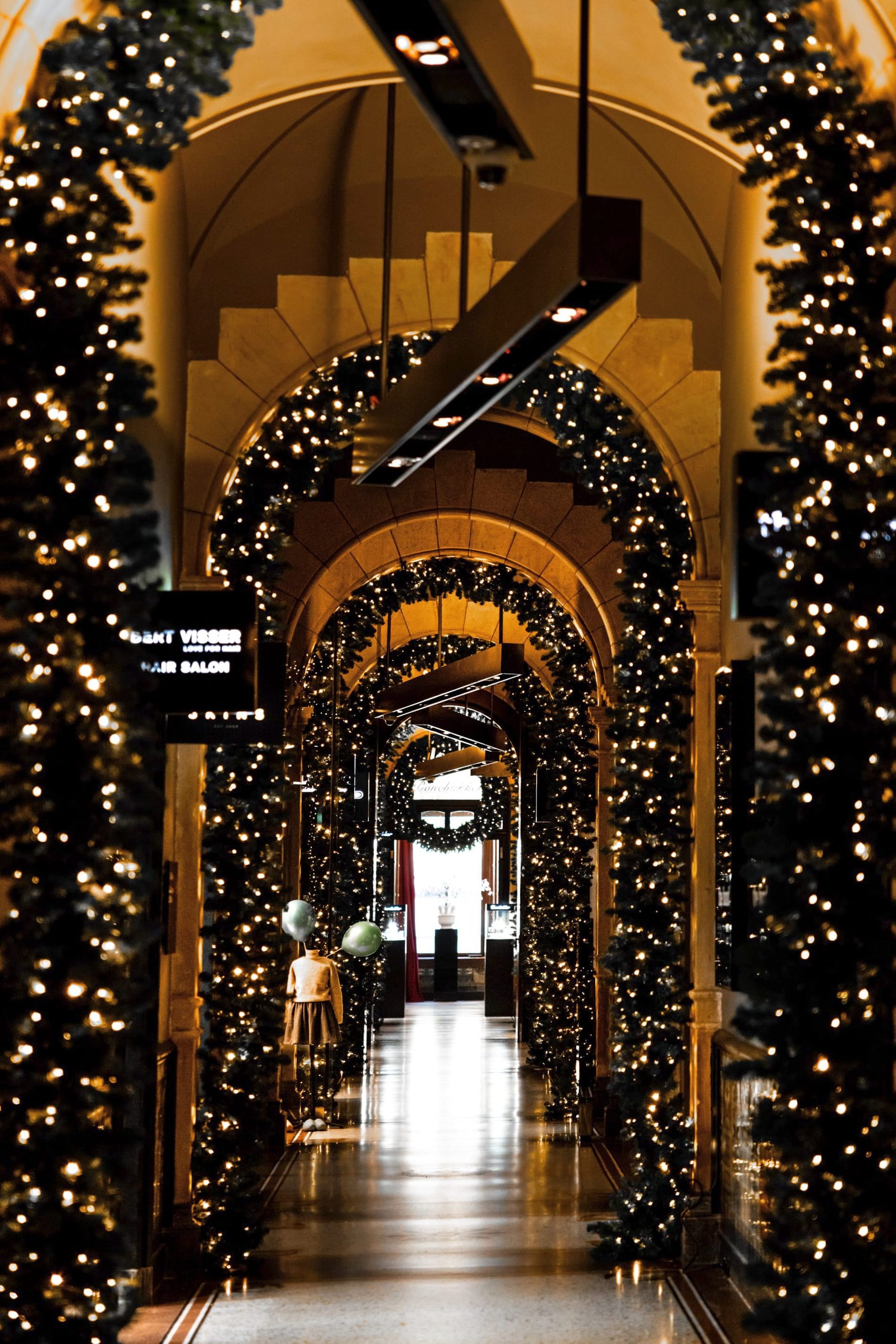 Festlich beleuchteter Hotelkorridor mit Weihnachtsbäumen und Lichterketten im Conservatorium Hotel Amsterdam.
