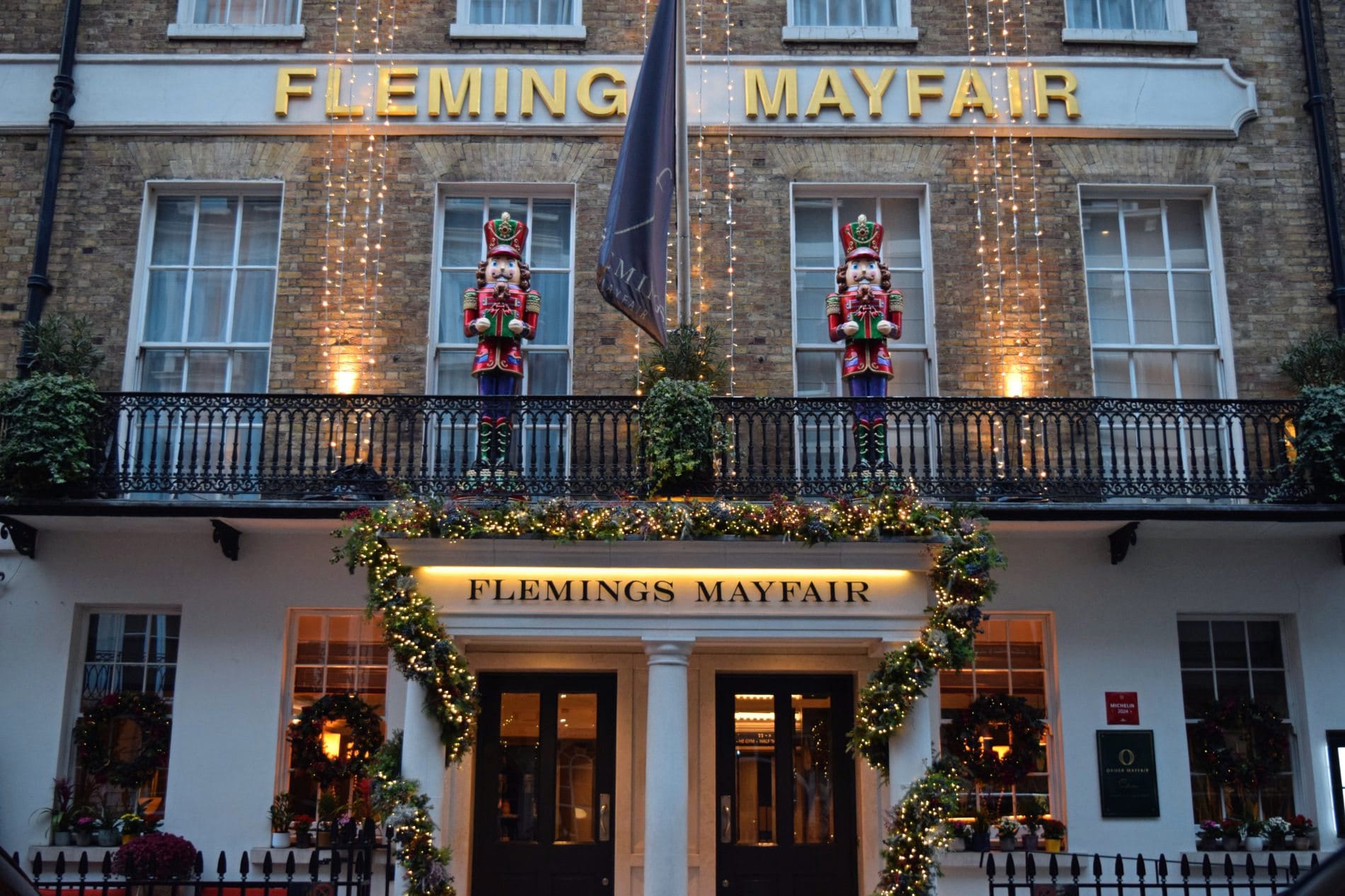 Fassade des Flemings Mayfair Hotels mit Weihnachtsbeleuchtung, Nussknacker-Figuren und festlich geschmücktem Eingang.
