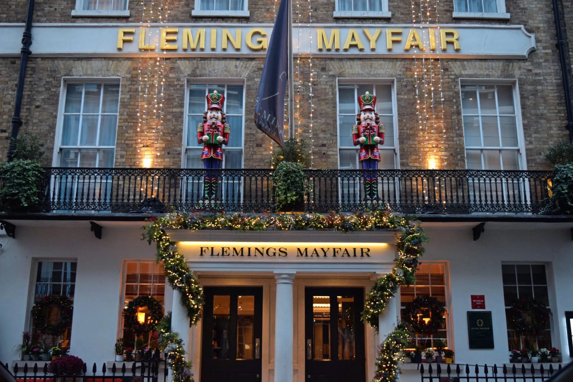 Fassade des Flemings Mayfair Hotels mit Weihnachtsbeleuchtung, Nussknacker-Figuren und festlich geschmücktem Eingang.