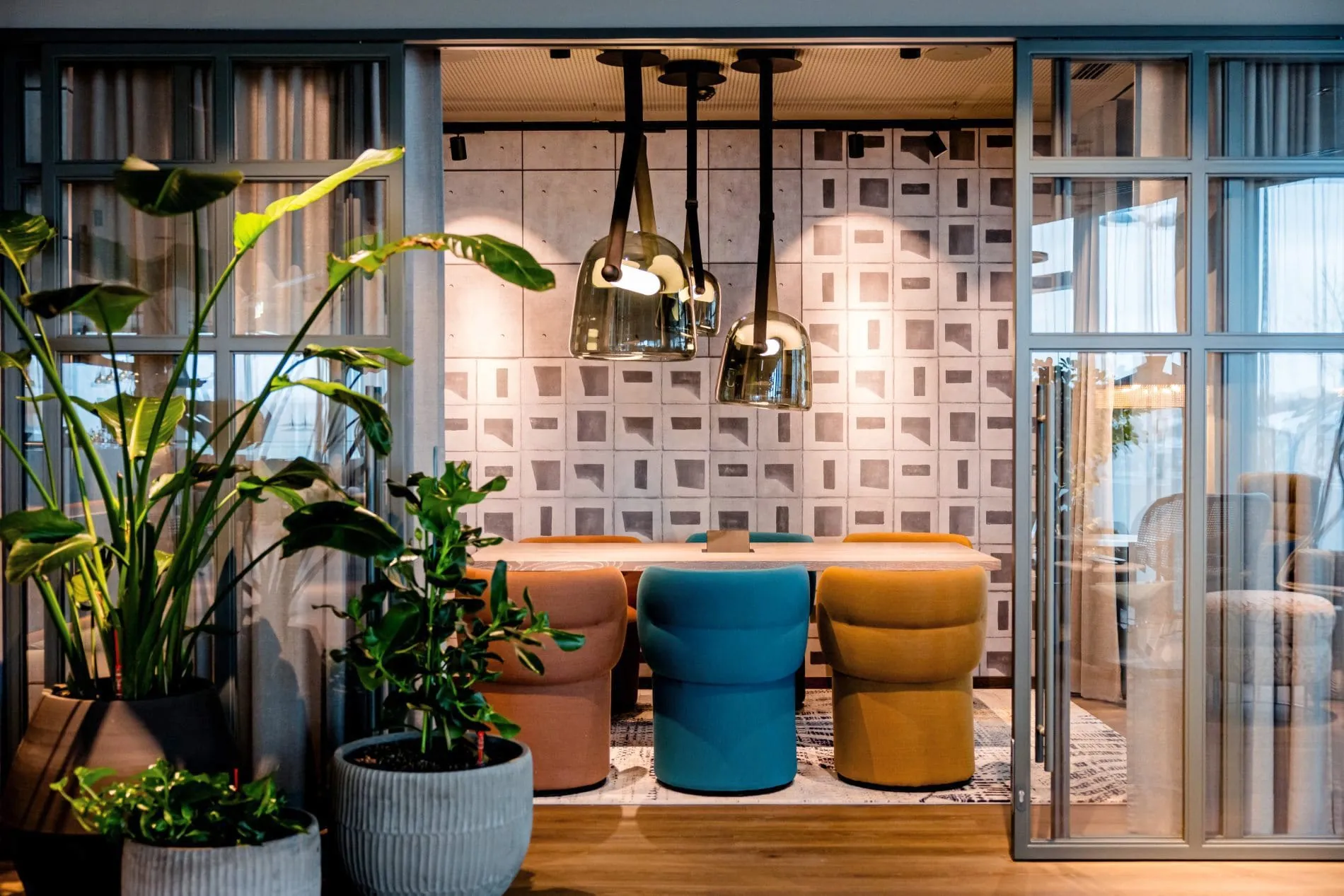 Abgetrennter Sitzbereich mit bunten Hockern, Pendelleuchten und Pixel-Wandgestaltung.