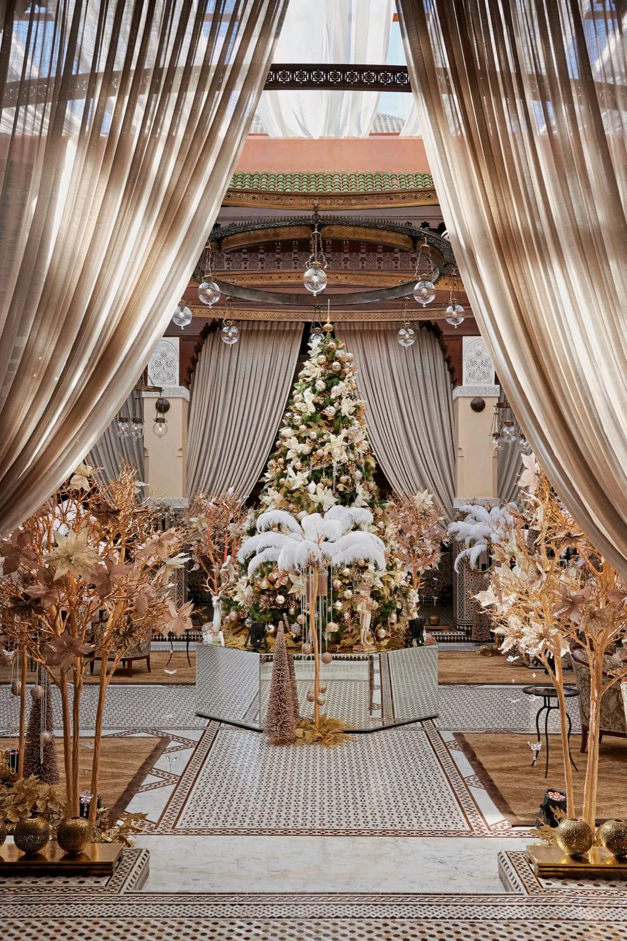 Festlich dekorierter Innenhof im Royal Mansour Marrakesch mit Weihnachtsbaum, goldenen Bäumen und marokkanischer Architektur.