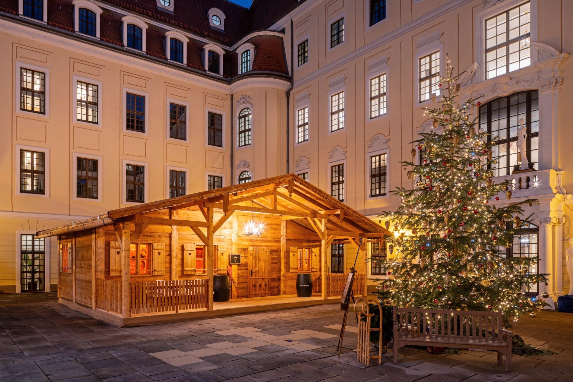 Beleuchtete Holz-Almhütte mit Weihnachtsbaum im Innenhof des Taschenbergpalais Dresden zur Weihnachtszeit.