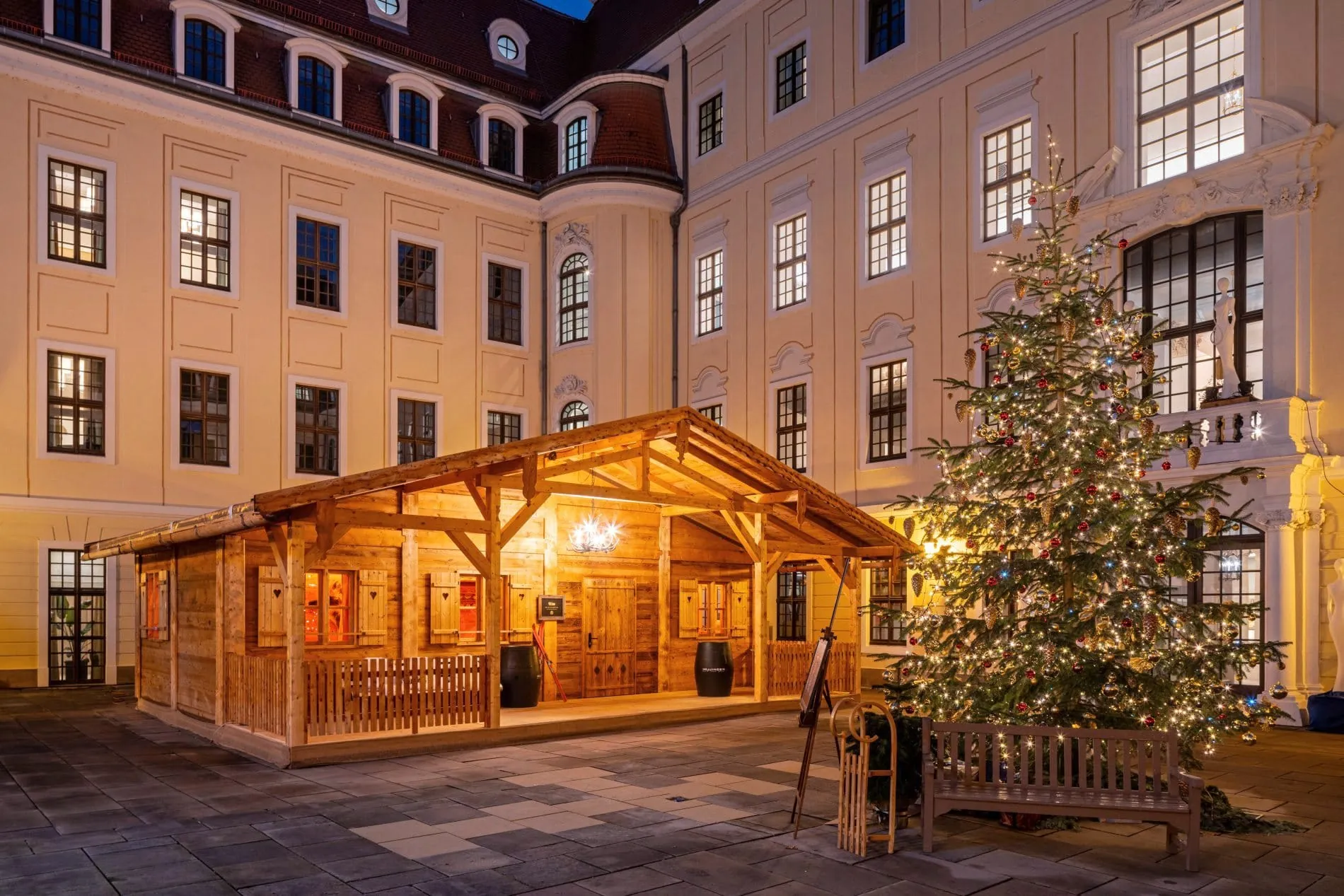 Beleuchtete Holz-Almhütte mit Weihnachtsbaum im Innenhof des Taschenbergpalais Dresden zur Weihnachtszeit.