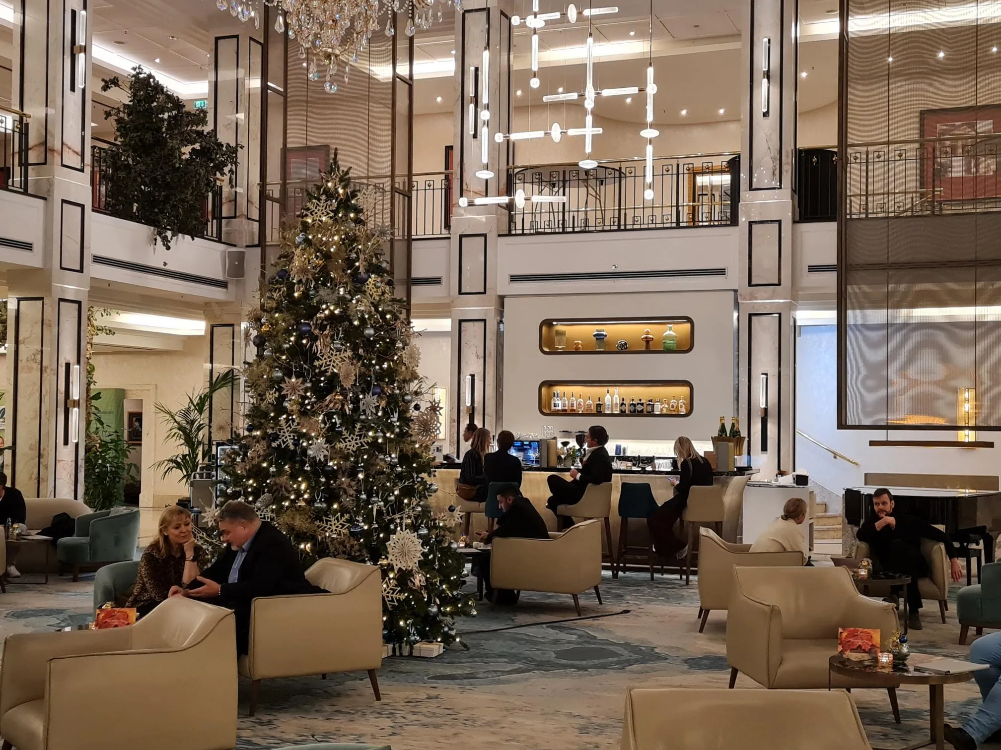 Lobby im JW Marriott Berlin mit Weihnachtsbaum, Lounge-Möbeln, modernen Leuchten und Empfangsbereich.