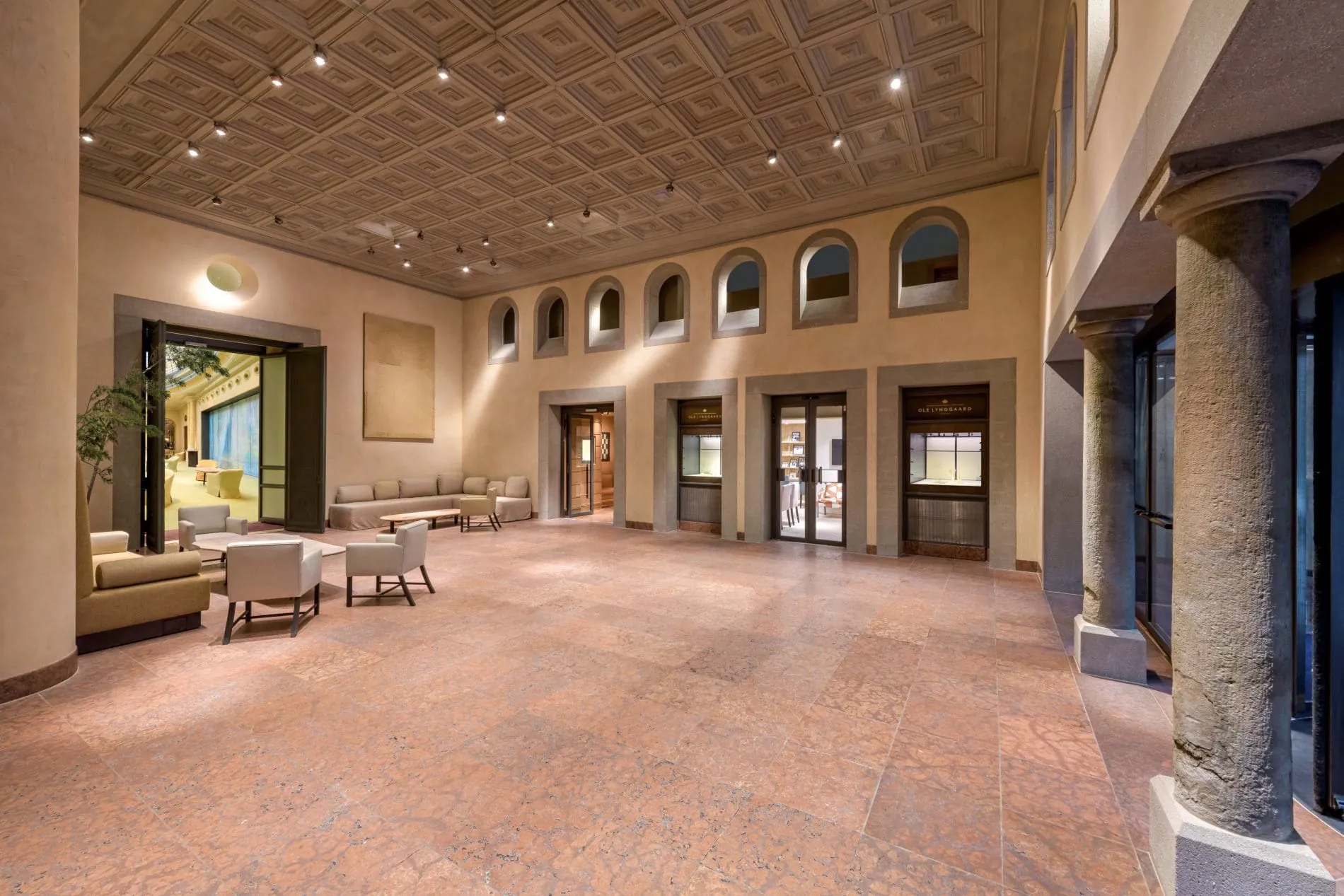 Die Kassettendecke schließt die Innenhoffassade nach oben ab und lässt den Raum wie einen nachträglich überdachten Innenhof wirken.