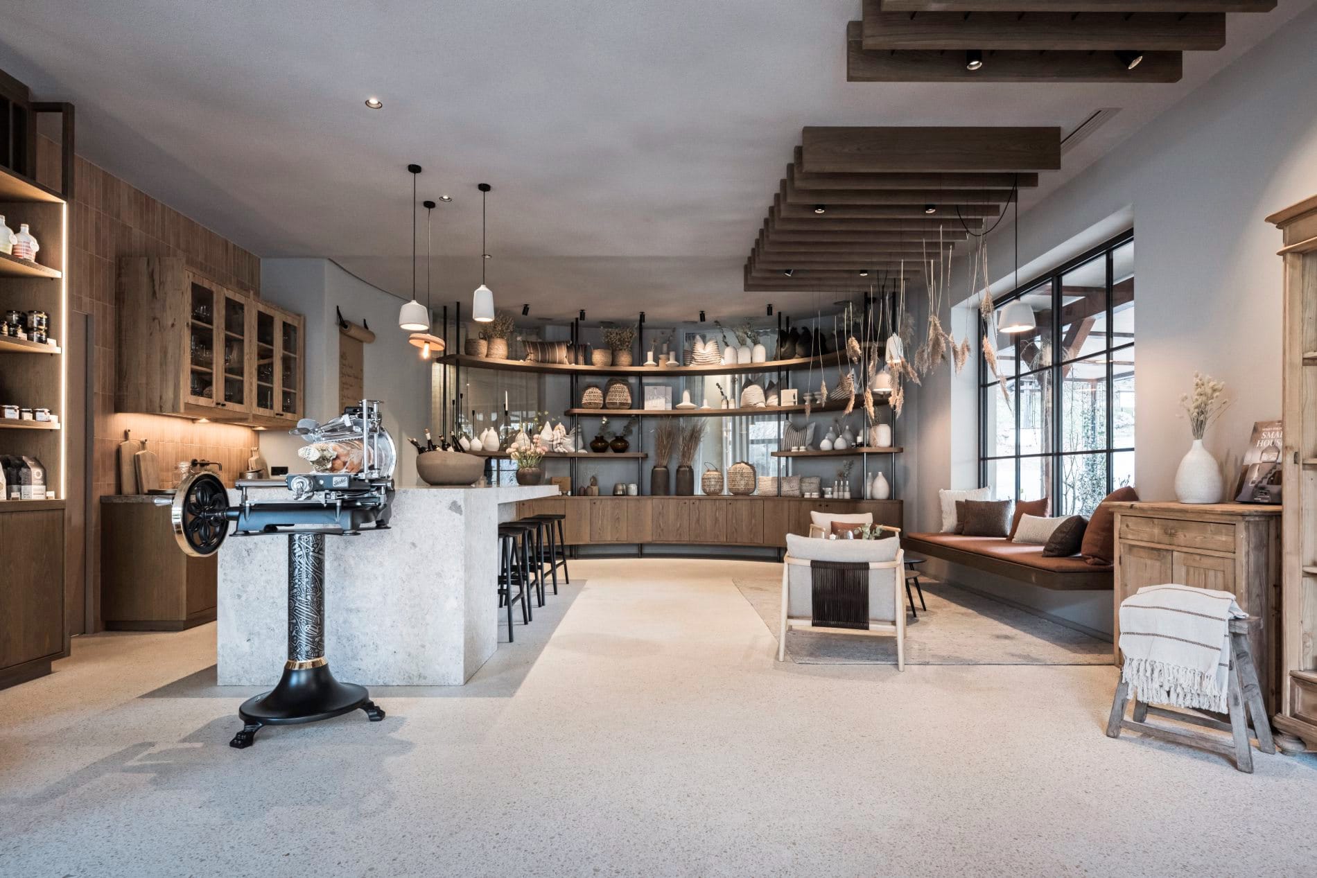 Offener Raum mit Steintresen, antiker Aufschnittmaschine, Regalen und Lounge-Bereich.