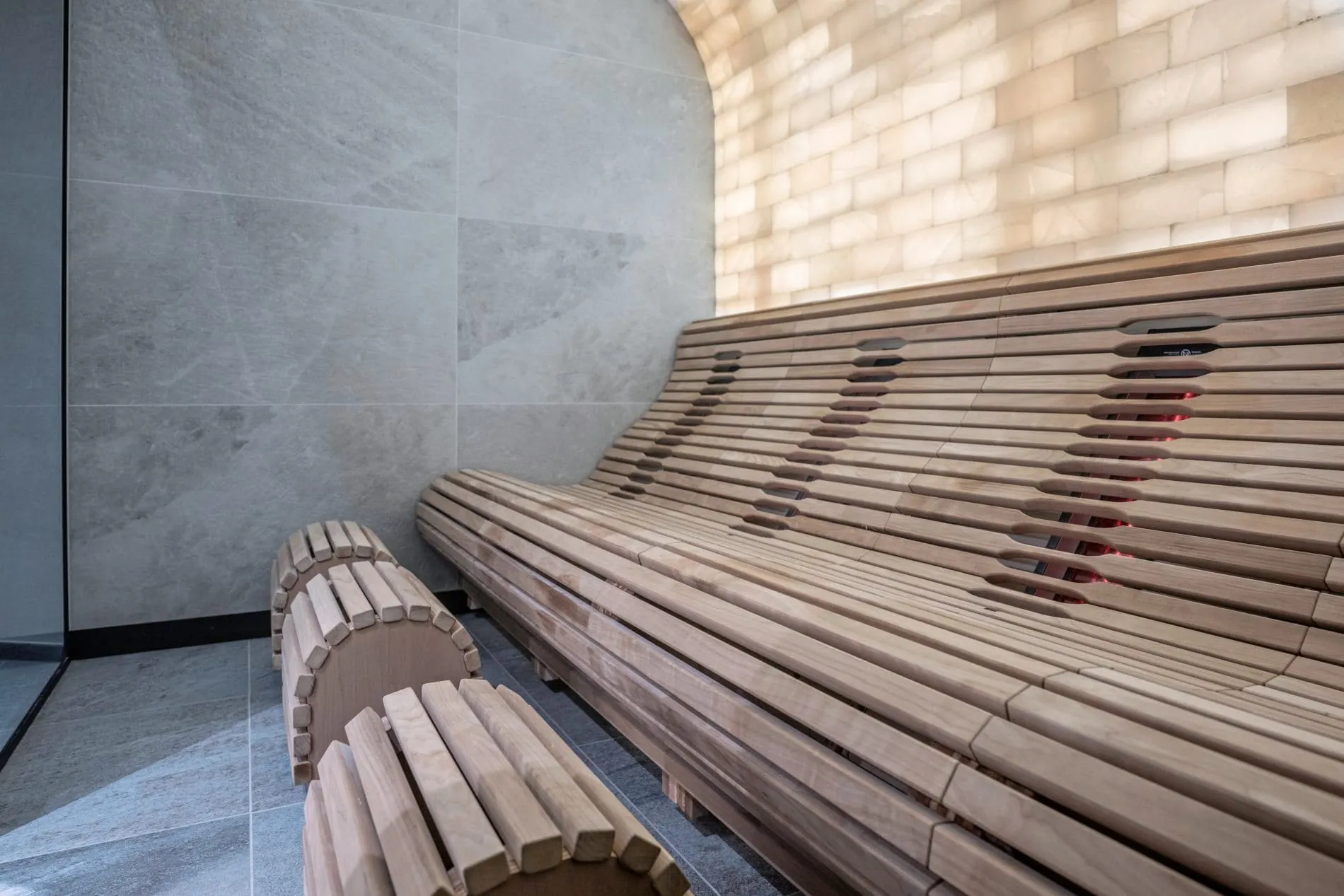 Sauna mit Holzliege und beleuchteter Salzsteinwand im Spa-Bereich.