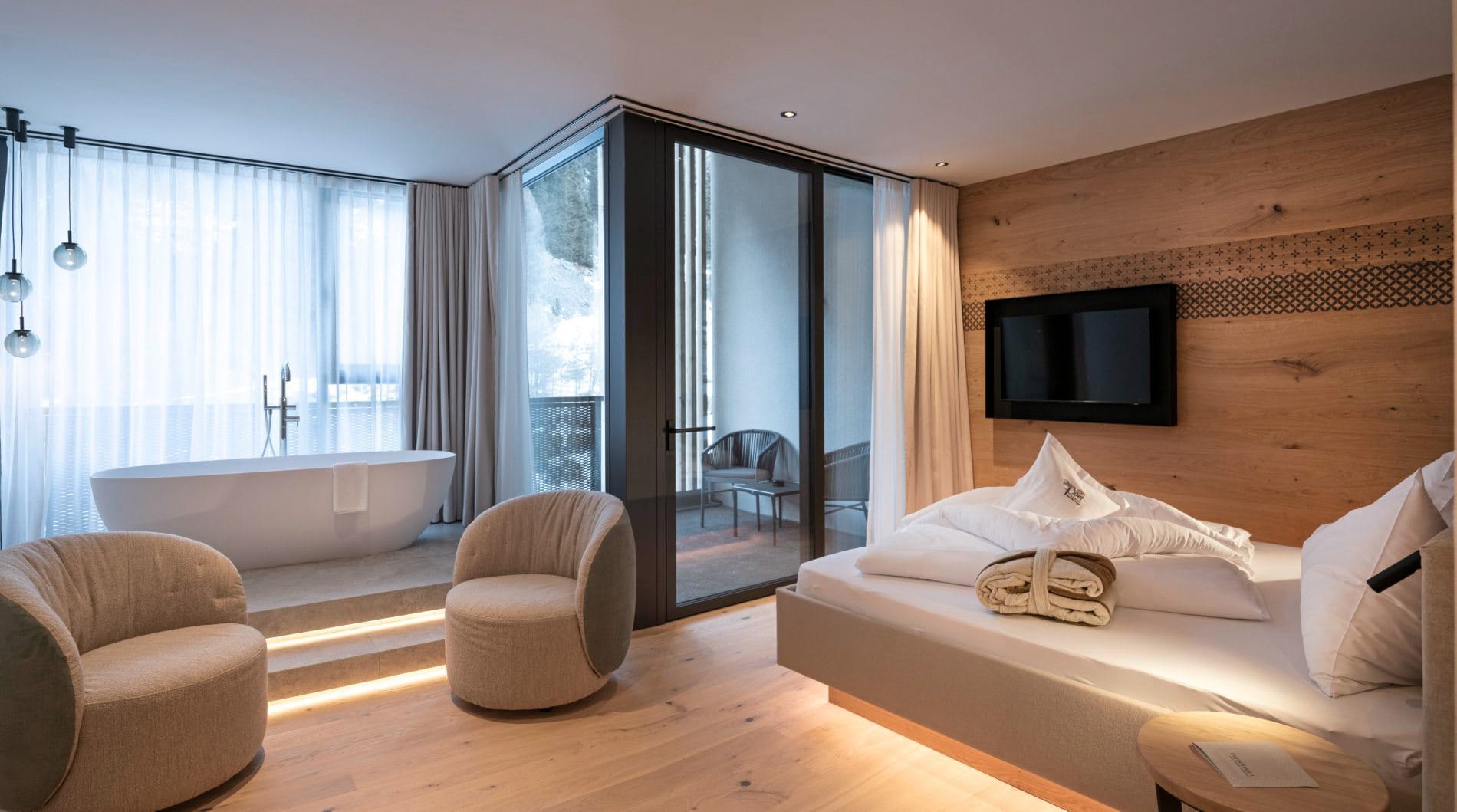 Juniorsuite mit Doppelbett, freistehender Badewanne und Balkonzugang.