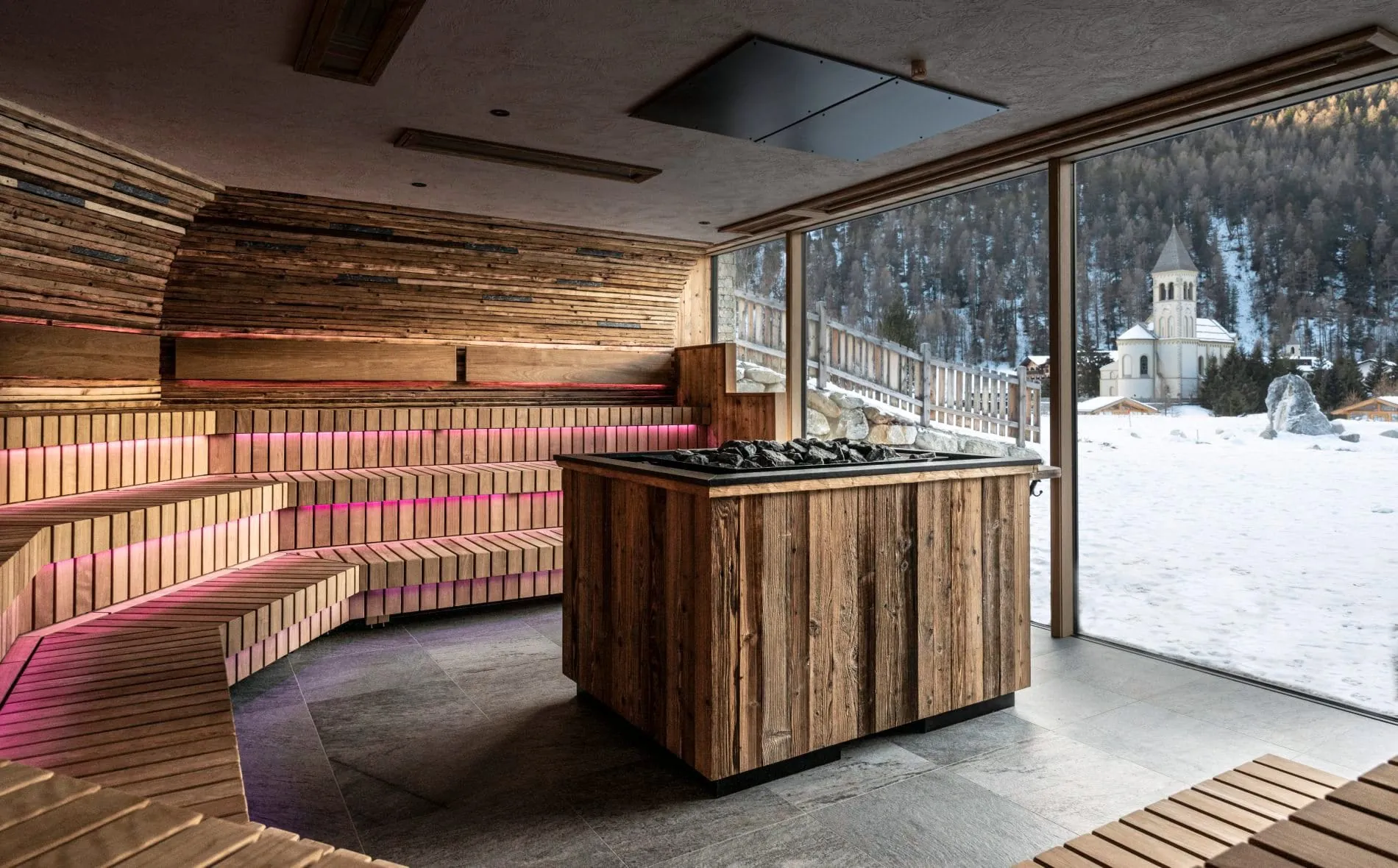 Holzsauna mit Saunaofen, LED-Beleuchtung und Panoramafenster mit Bergblick.