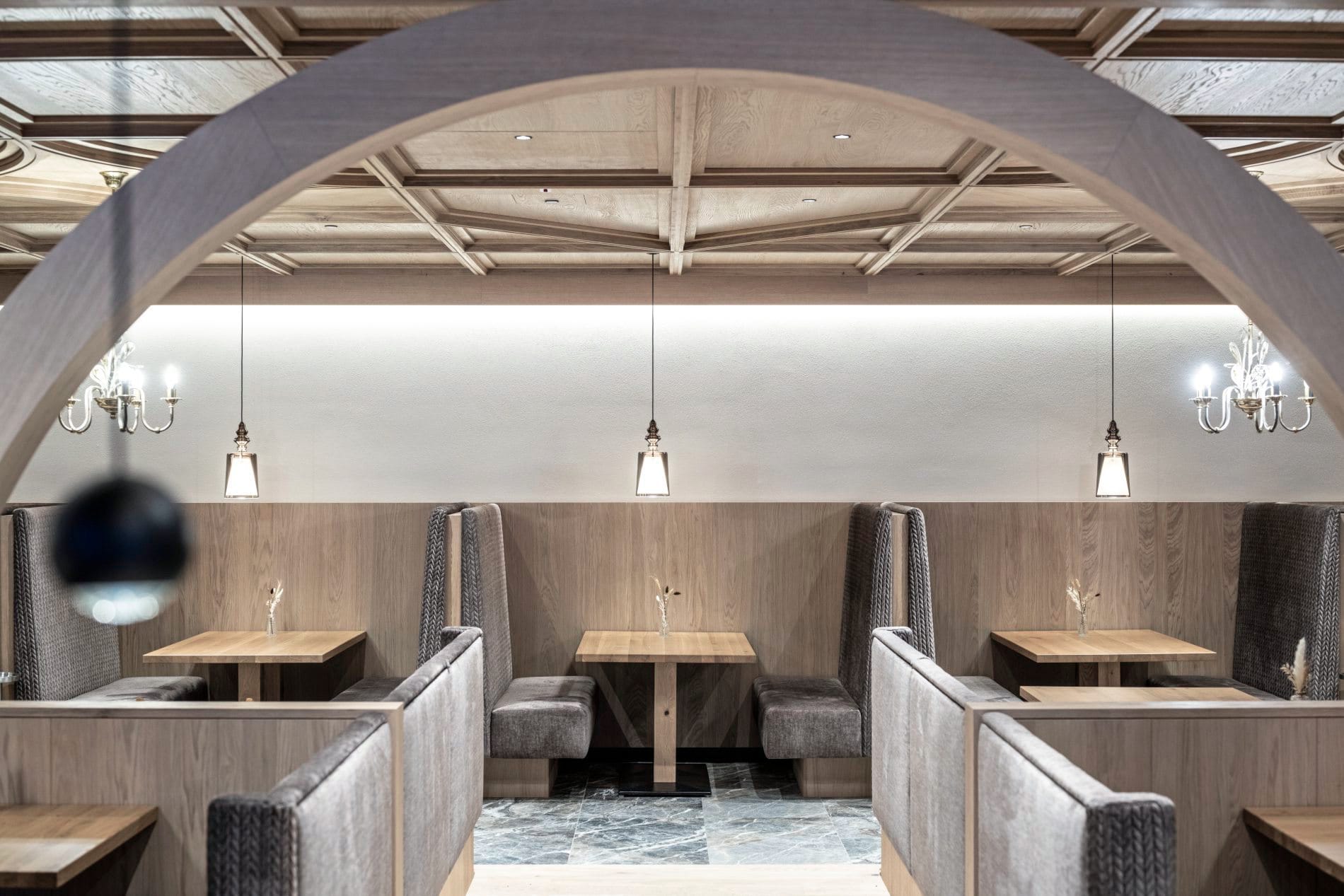 Restaurant mit gewölbter Holzdecke, Pendelleuchten und gepolsterten Sitznischen.