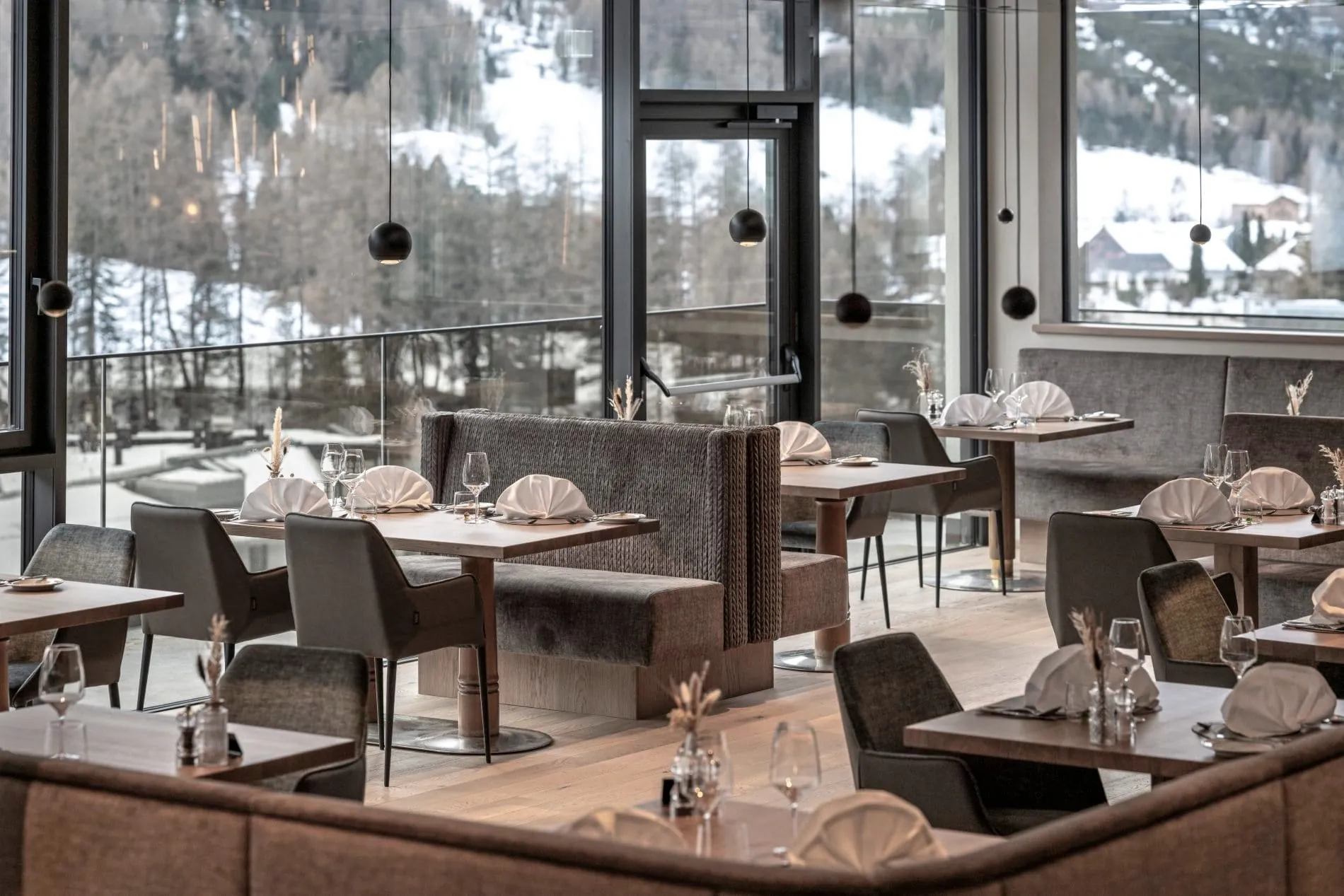 Hotelrestaurant mit gedeckten Tischen, Sitzbänken und Panoramafenstern.
