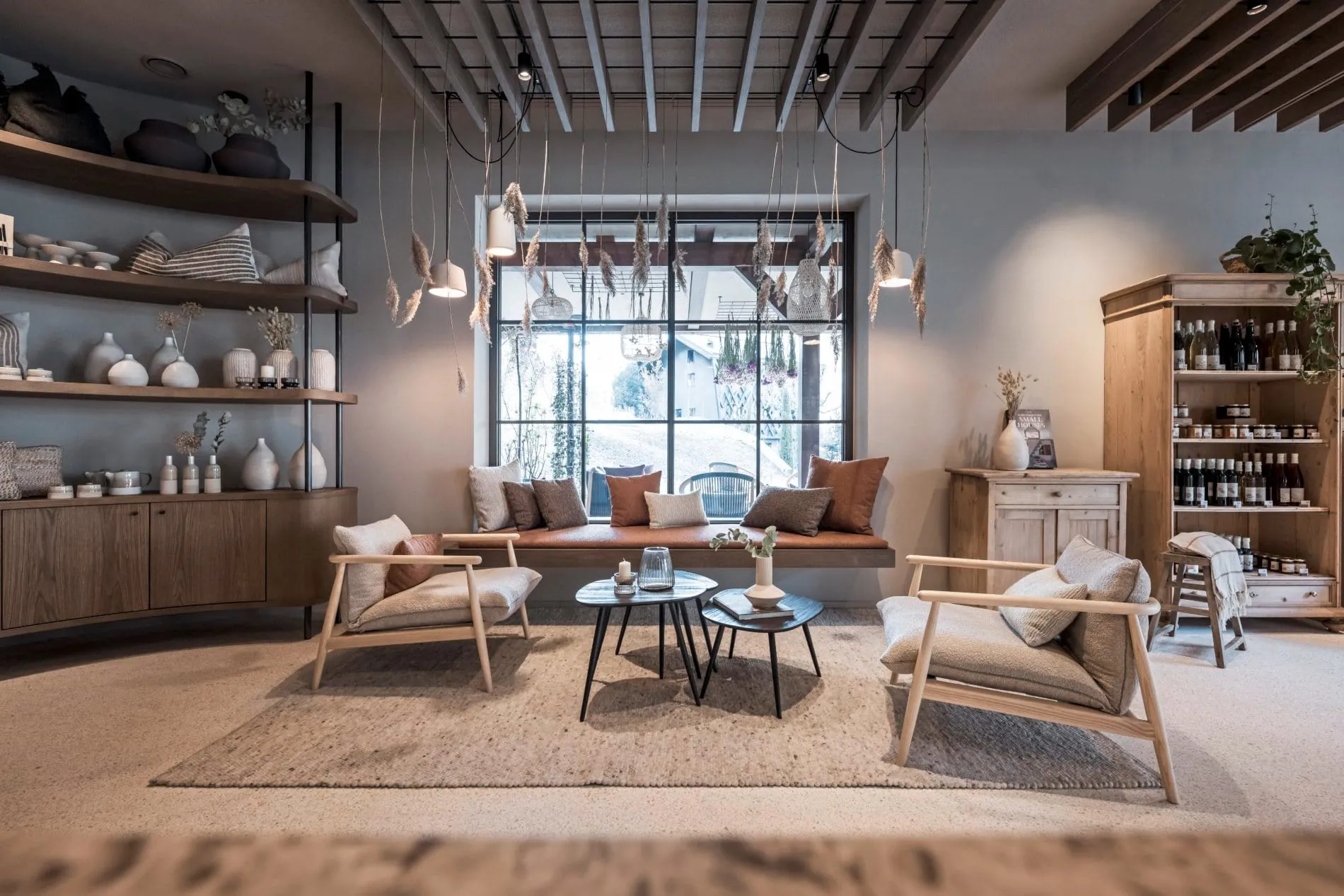 Lounge mit Sesseln, Fensterbank-Sofa, Dekoregalen und Trockenblumen-Dekoration.