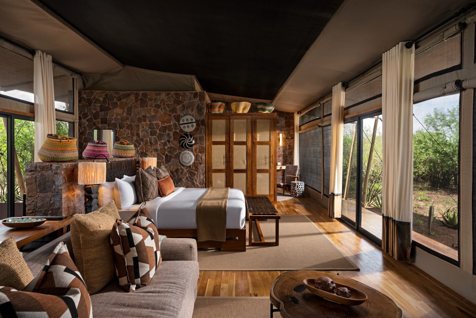 Gemütliche Zeltsuite mit Doppelbett, Natursteinwand und bunten handgeflochtenen Körben.