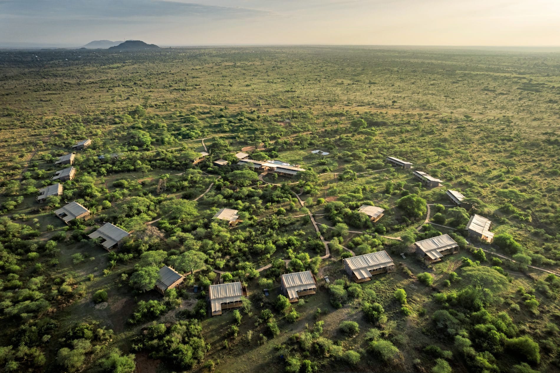 Luftaufnahme des Safari-Camps mit verteilten Zeltunterkünften inmitten grüner Buschlandschaft