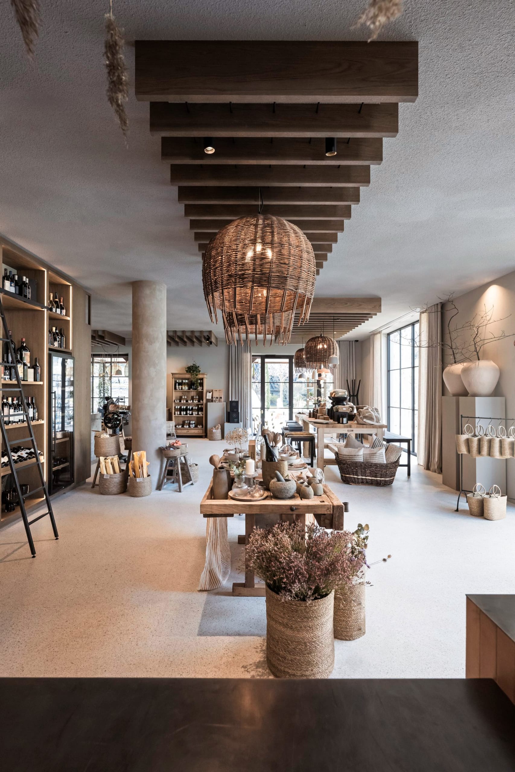 Terrakotta-Theke mit Blumenvasen, Weinregale im Hintergrund, Rattanleuchten.