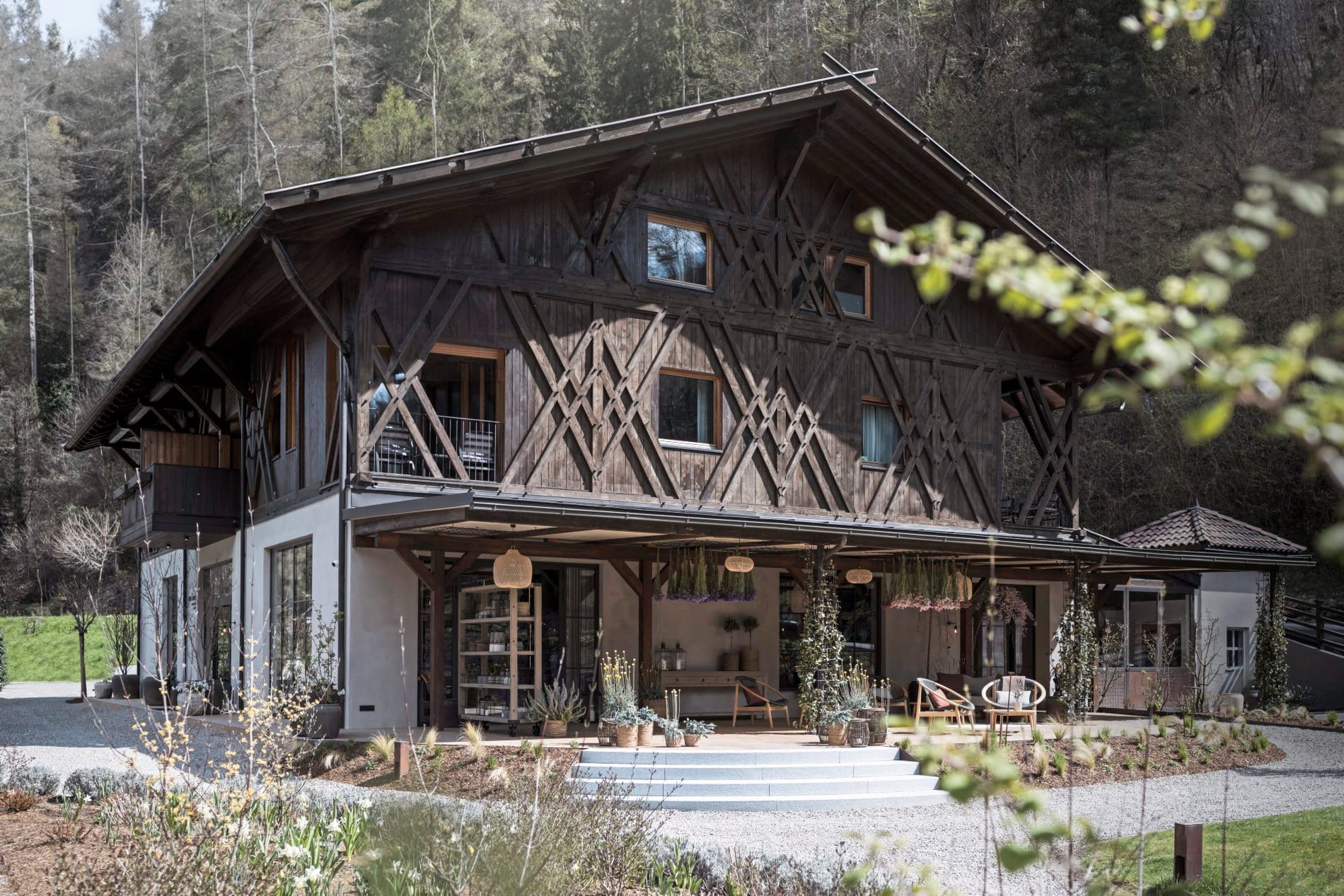 Traditioneller Südtiroler Stadel mit Holzfassade, überdachter Terrasse und Bergwald im Hintergrund.
