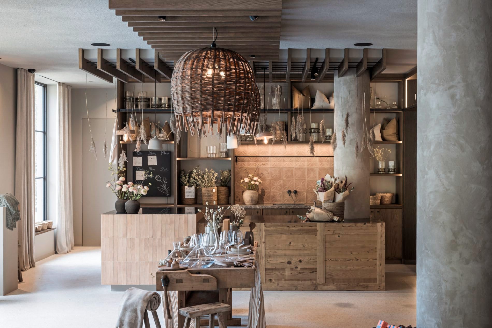 Floristenbereich mit Holzmöbeln, Blumenarrangements, Rattanleuchte und Wochenplan-Tafel.
