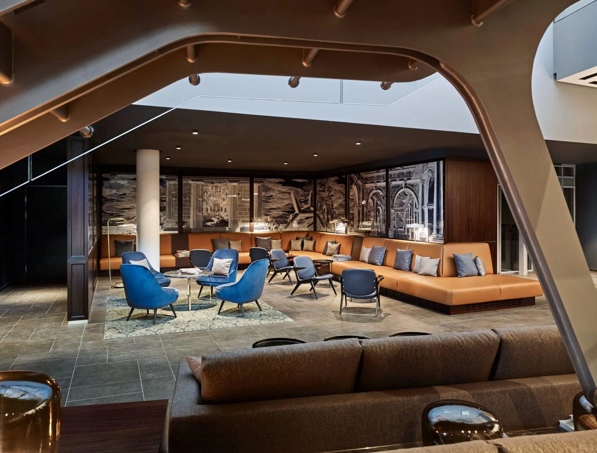 Lobby Lounge mit Ledersofas, blauen Sesseln und historischer Wandkunst im Andaz Vienna.