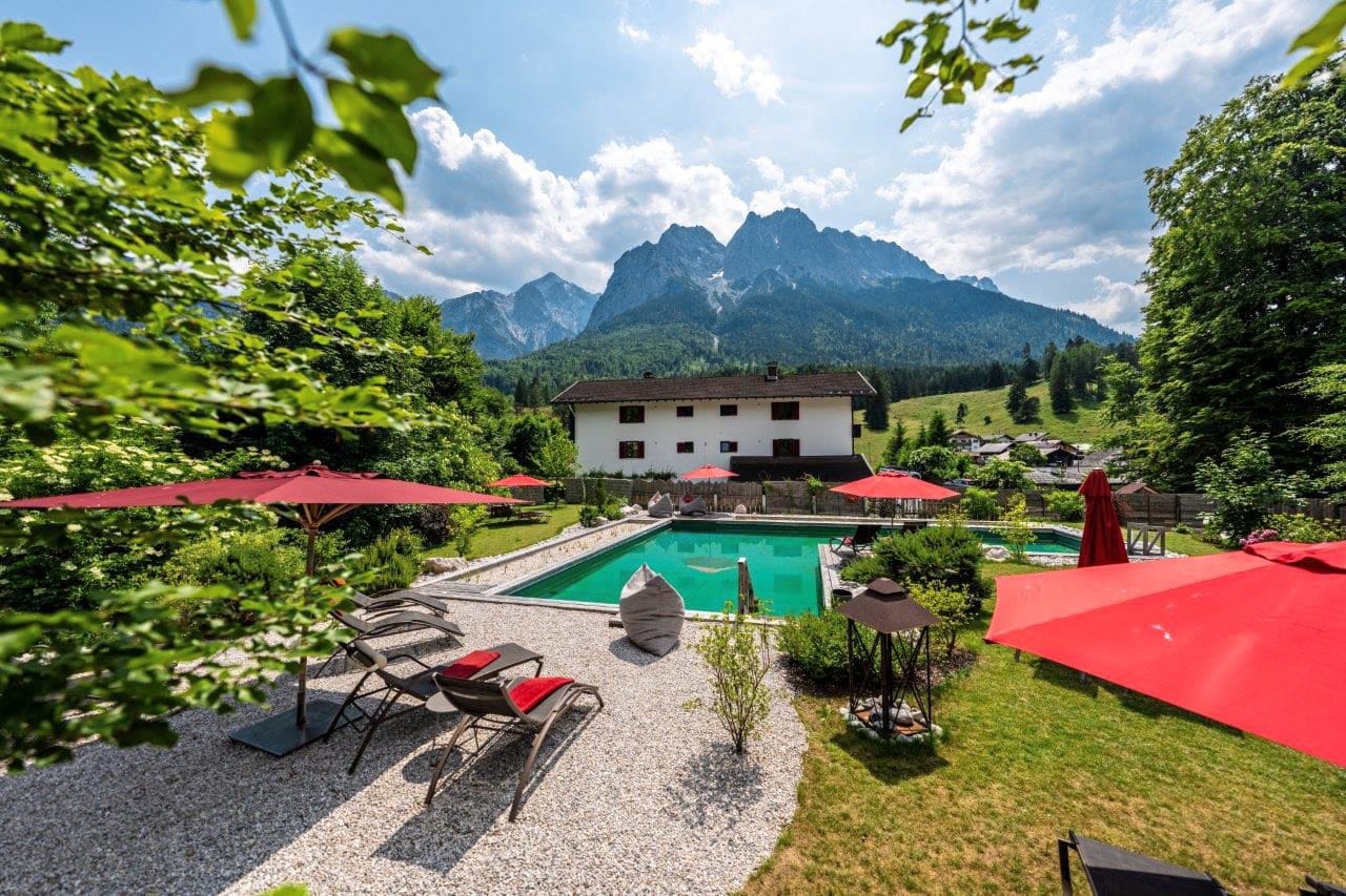 Der Pool des Bayern Resorts – Die Urlaubsmanufaktur in Grainau bietet Blick auf die umliegende Berglandschaft. Das Quellwasser des 200 Kubikmeter großen Naturpools wird biologisch aufbereitet und kommt ohne chemische Zusätze aus.