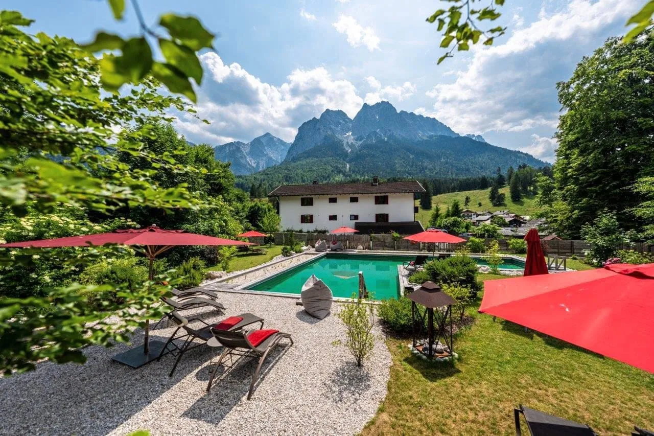 Der Pool des Bayern Resorts – Die Urlaubsmanufaktur in Grainau bietet Blick auf die umliegende Berglandschaft. Das Quellwasser des 200 Kubikmeter großen Naturpools wird biologisch aufbereitet und kommt ohne chemische Zusätze aus.