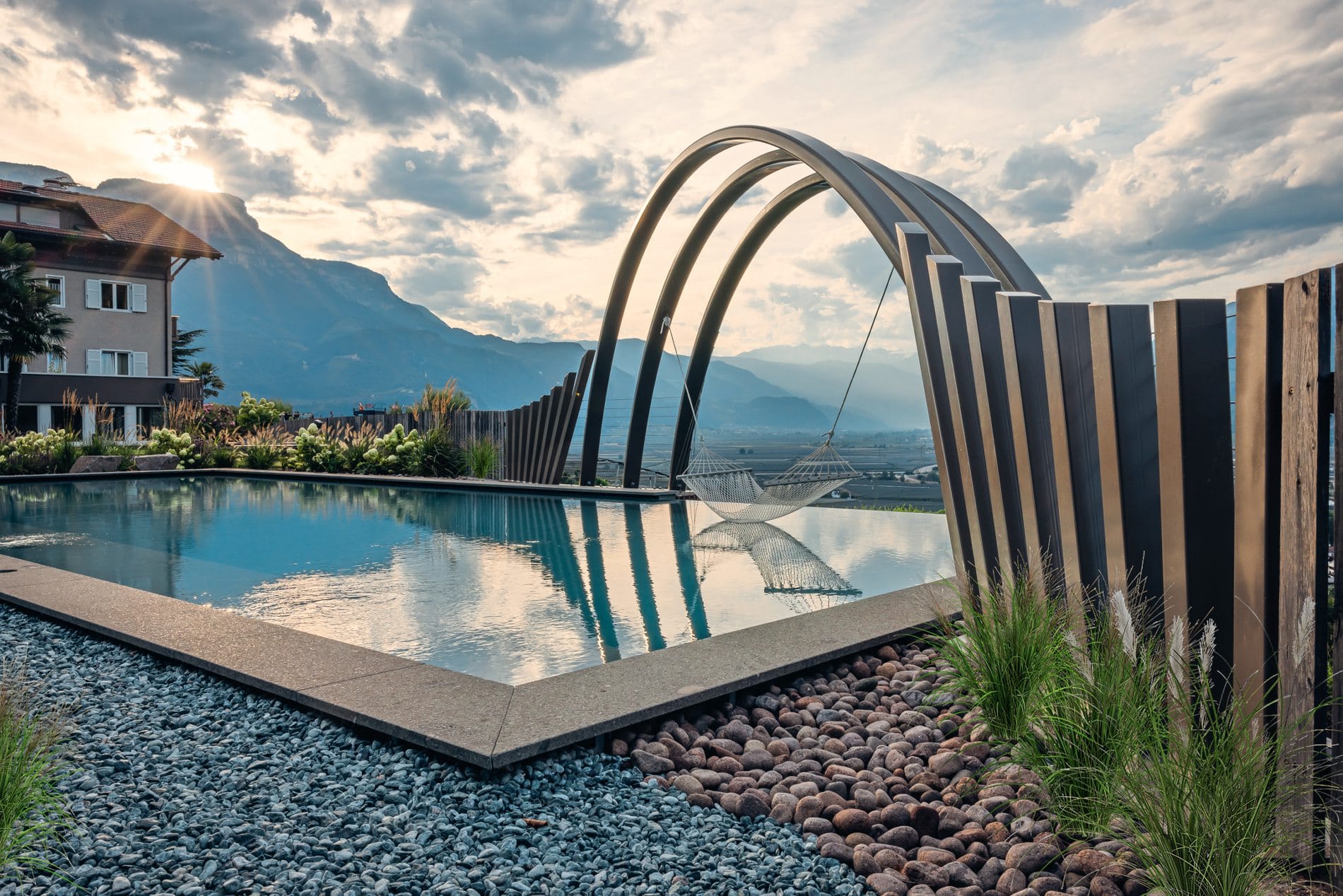 Der Infinitypool des Hotels Sigmundskron in Frangart ist in eine Gartenanlage mit Blick auf Schloss Sigmundskron eingebettet - eingerahmt von einem Gartenbogen mit Hängematte.