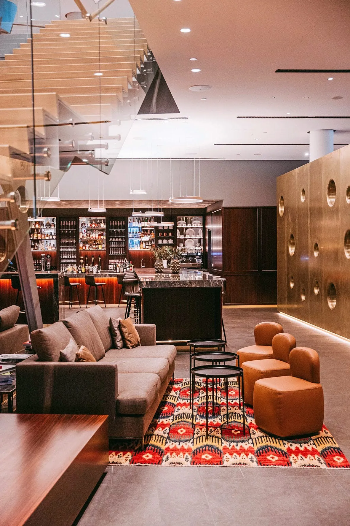 Lobby Lounge mit Bar, Ledersesseln, Sofa und buntem Teppich im Andaz Vienna.