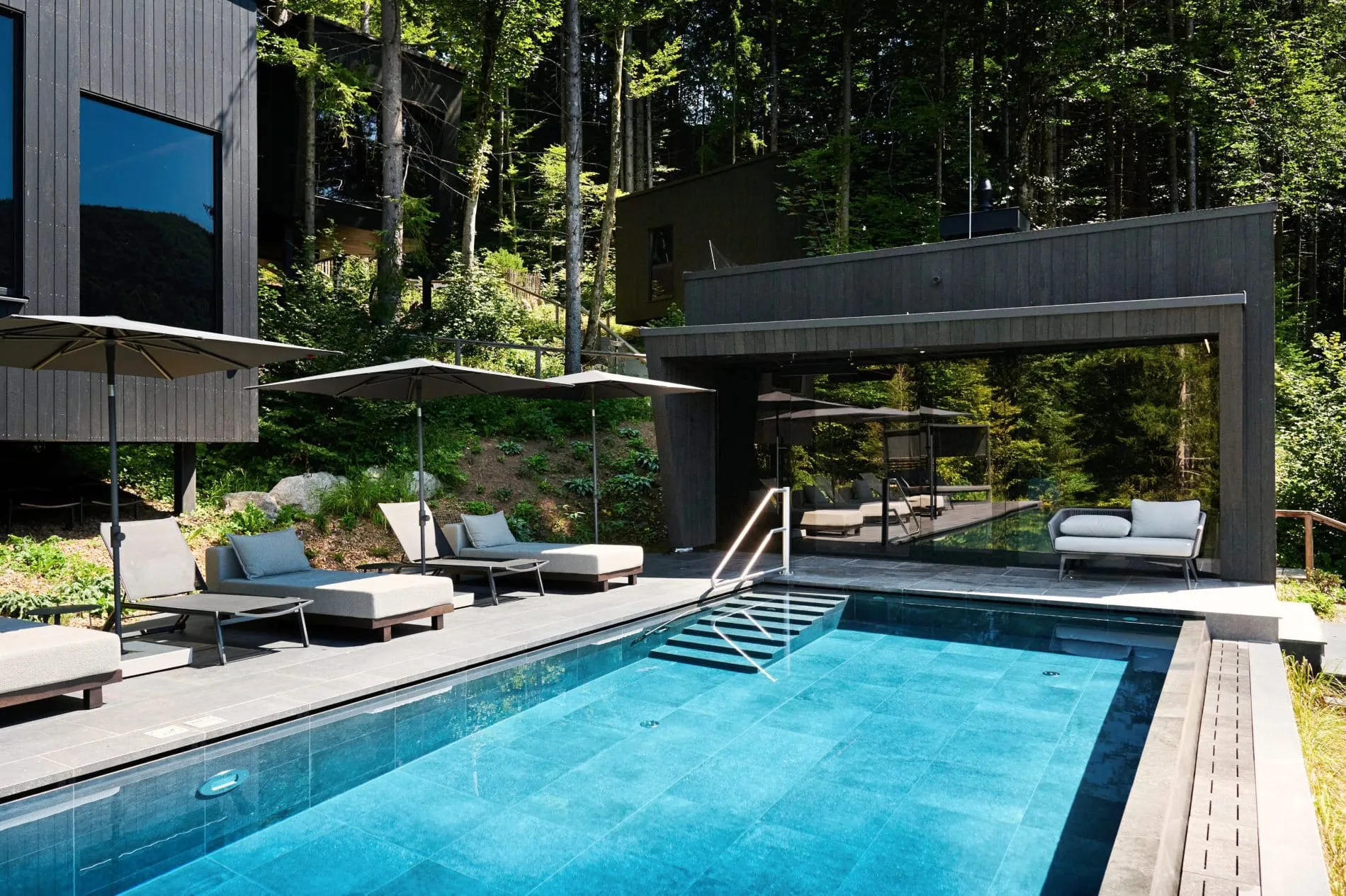 Der ganzjährig beheizte Outdoor-Infinitypool des Naturhotels Fischerwirt in Faistenau liegt zwischen Mischwald und dem Hintersee. Seit dem Umbau 2025 ist er Teil des hoteleigenen Waldspa-Bereichs.