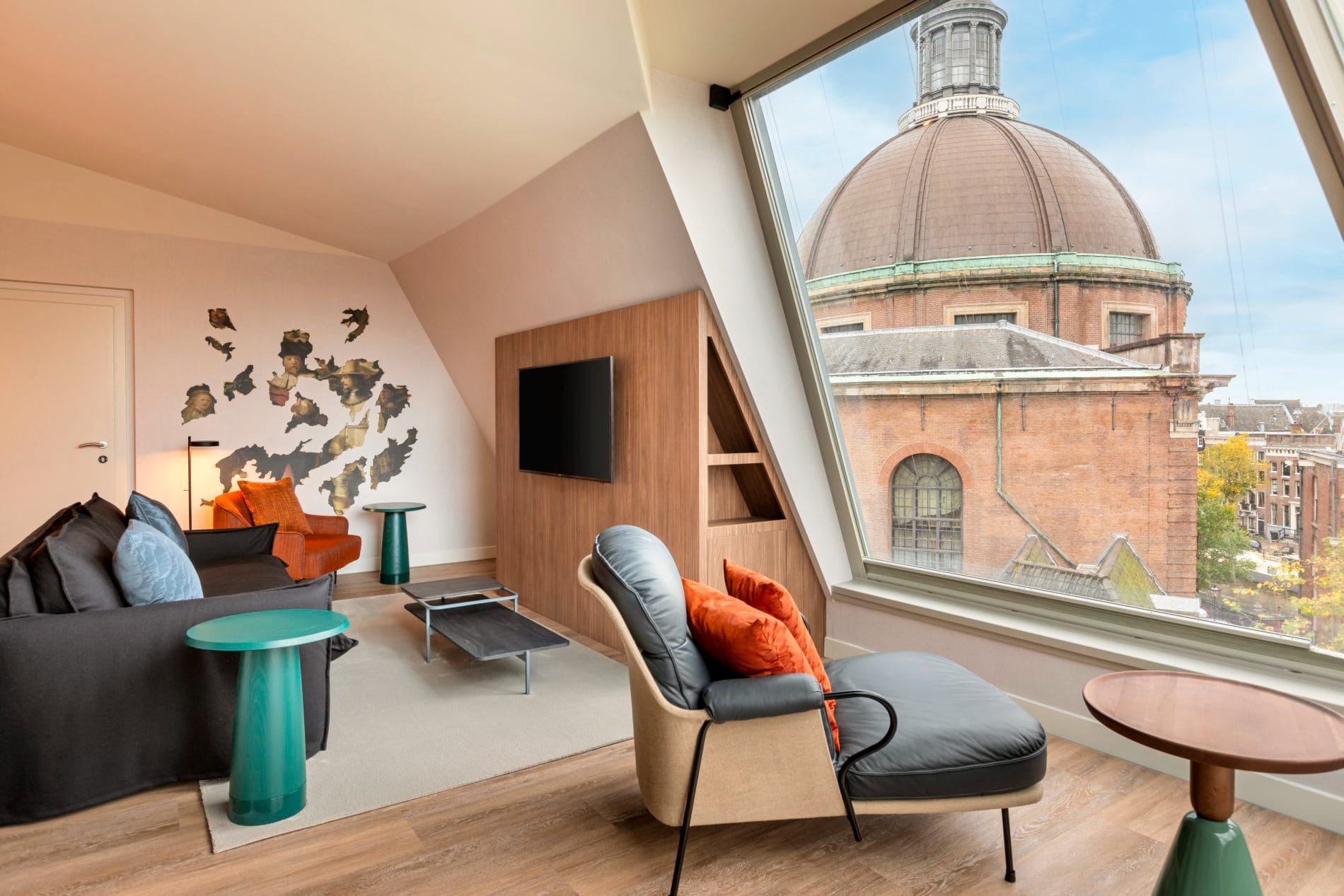 Elegante Hotelsuite mit Panoramafenster, Blick auf Koepelkerk-Kuppel, moderne Möbel in Orange und Grau.