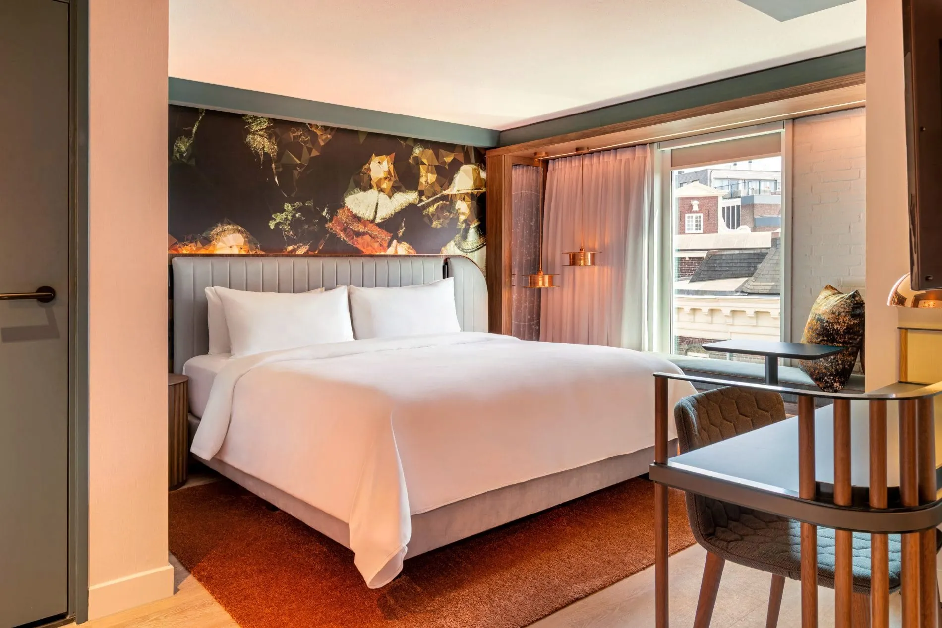 Hotelzimmer mit Doppelbett, Kunstwand im Rembrandt-Stil, Schreibtisch und Fensterplatz.