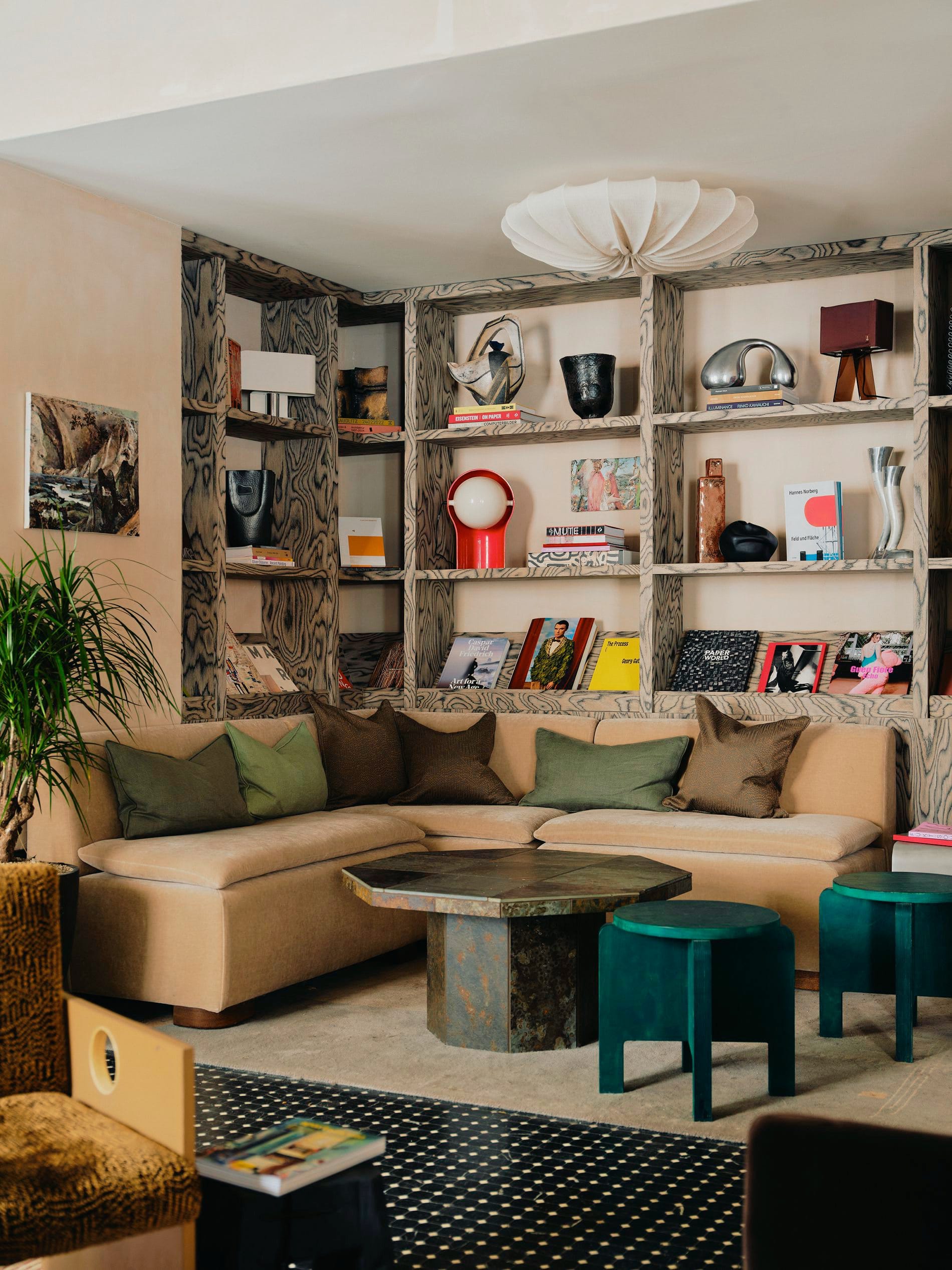 Stylisher Loungebereich: Ein raumhohes Regal aus marmoriertem Holz präsentiert Kunstbücher, Designobjekte und Lampen.