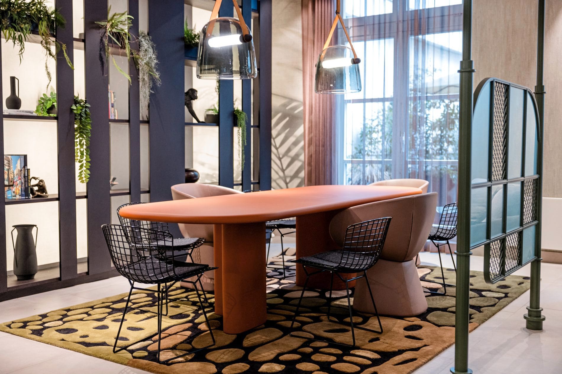 Workbench im Motel One Frankfurt mit orangefarbenem Designtisch, Drahtgeflechtstühlen und Regal