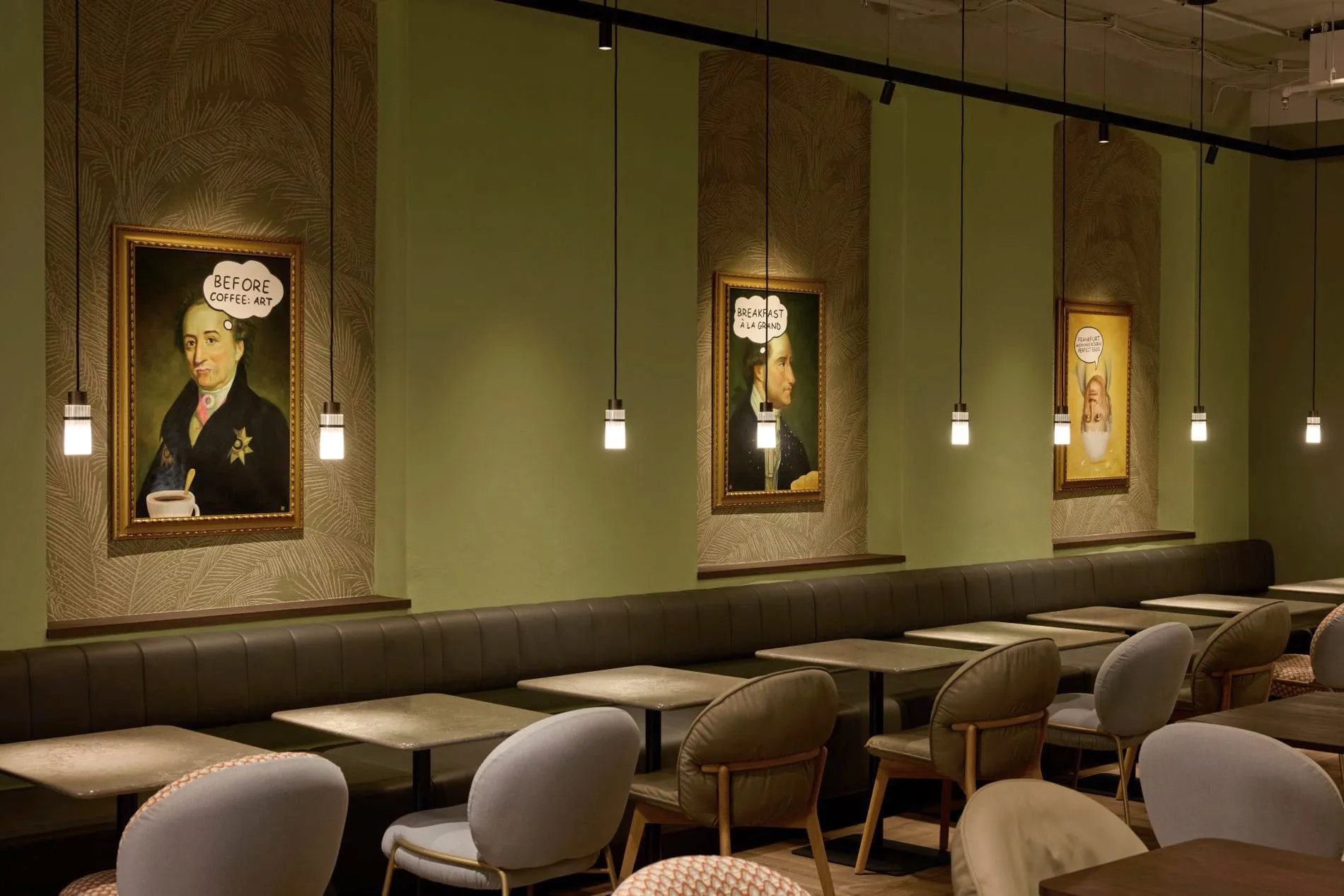 Frühstücksraum mit grünen Wänden, Goethe-Porträts mit Comic-Sprechblasen und gepolsterten Sitzbänken.