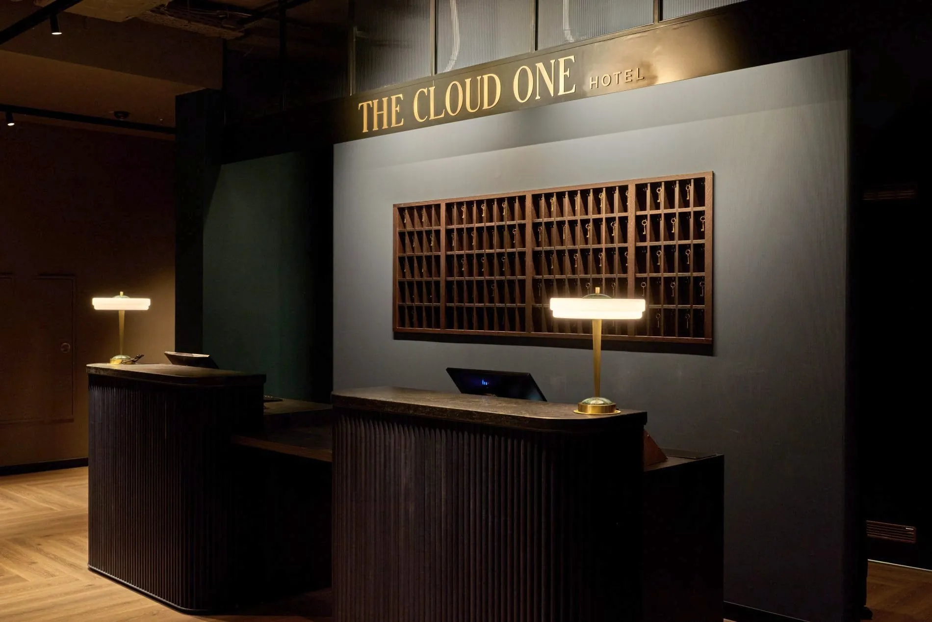 Rezeption des The Cloud One Frankfurt-Metropolitan mit goldenem Schriftzug, Schlüsselkasten und Messinglampen