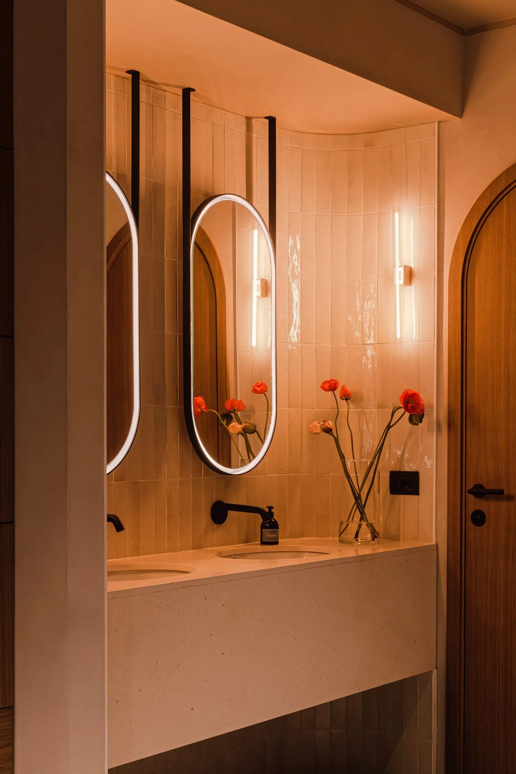 Hinterleuchtete Ovalspiegel und schwarze Armaturen verleihen den Badezimmern des Hotels einen modernen Look.