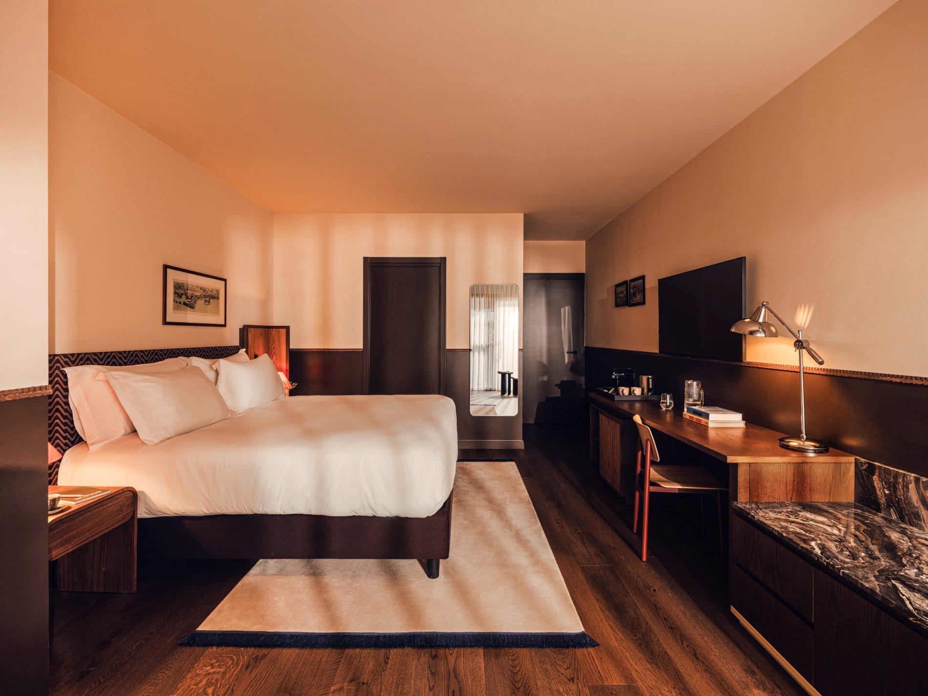 Warme Erdtöne, Chevron-Kopfteile und maßgefertigte Holzmöbel prägen die Junior Suite – ein Beispiel für die 35 individuell gestalteten Zimmer des Hotels.