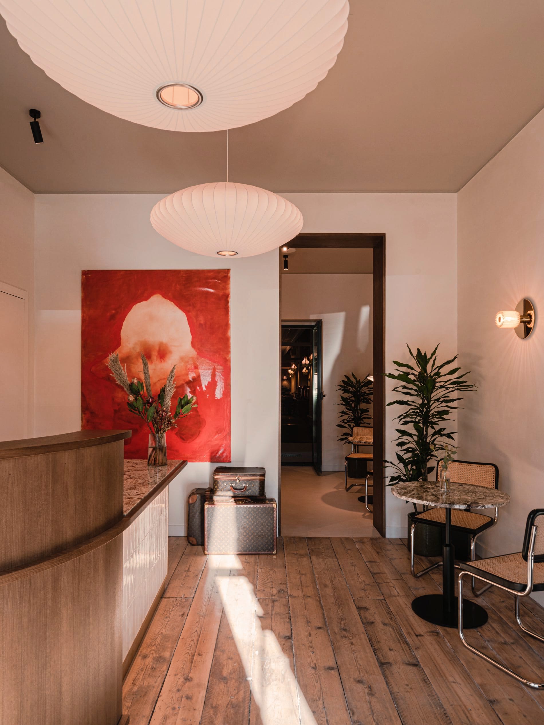 Der Empfangsbereich setzt mit großformatiger Kunst, Nelson-Bubble-Leuchten und Designerkoffer-Deko den Ton für das Hotel in Milan.