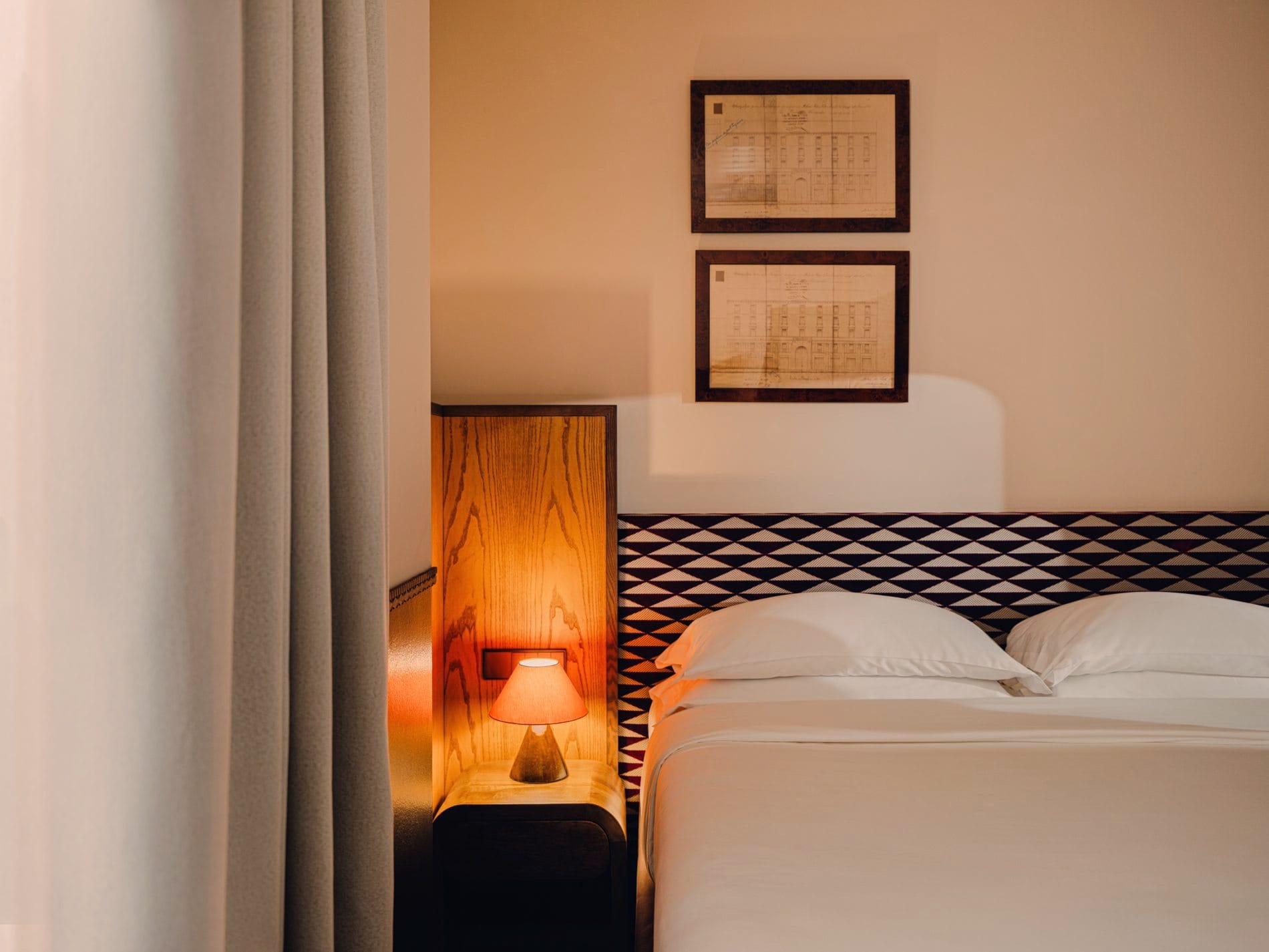 Maßgefertigte Kopfteile mit geometrischem Dreiecksmuster und integrierte Holz-Nachttische prägen das neue Zimmerdesign des Aethos Milan – ein ruhiger Gegenpol zum lebhaften Navigli-Viertel.