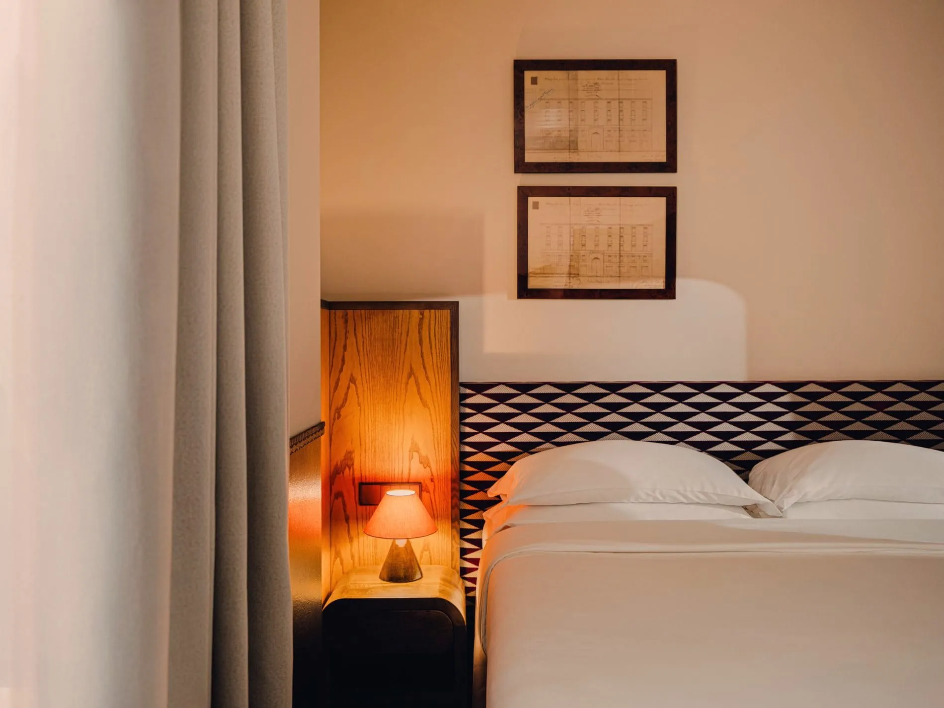 Maßgefertigte Kopfteile mit geometrischem Dreiecksmuster und integrierte Holz-Nachttische prägen das neue Zimmerdesign des Aethos Milan – ein ruhiger Gegenpol zum lebhaften Navigli-Viertel.